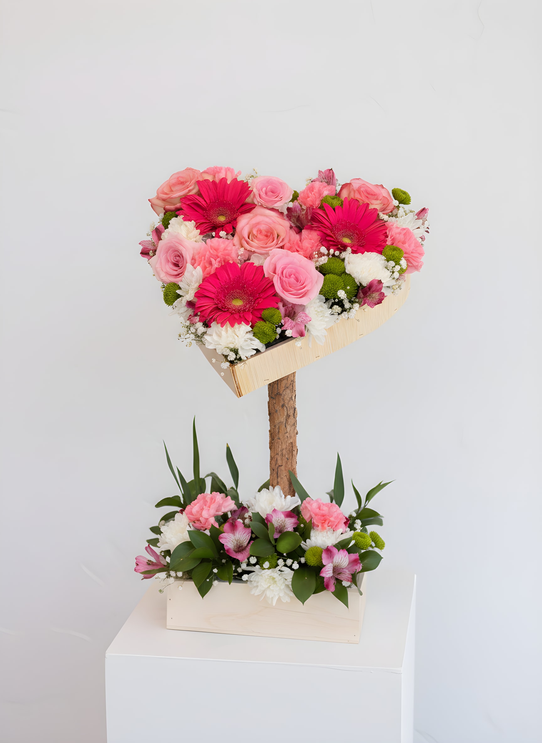 Pink Garden  - Romantic, unique, and full of thoughtful detail—this pink arrangement is beautifully designed in a handcrafted wooden display featuring two tiers. A charming heart-shaped topper rises above on a wooden stem, while a sturdy square wooden base holds the lush arrangement below, creating a striking layered look.
