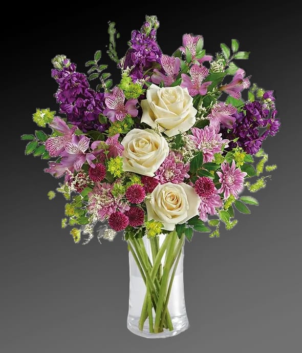 Bouquet of white roses, purple flowers, and pink blooms in a clear vase