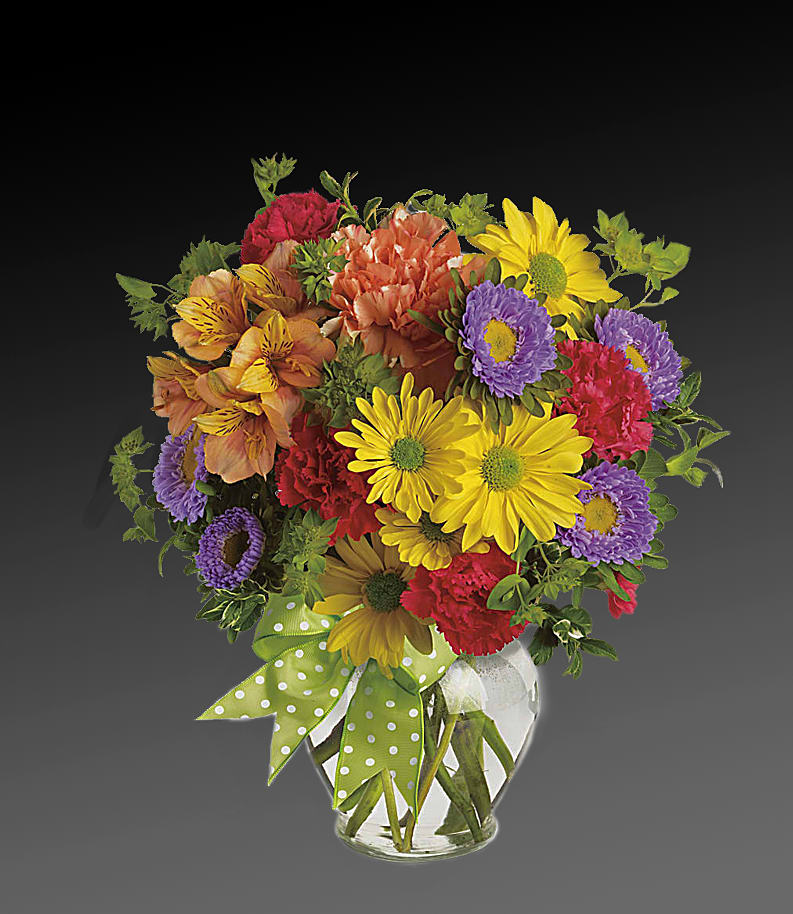 Colorful mixed bouquet in a clear glass vase with a green polka-dot ribbon