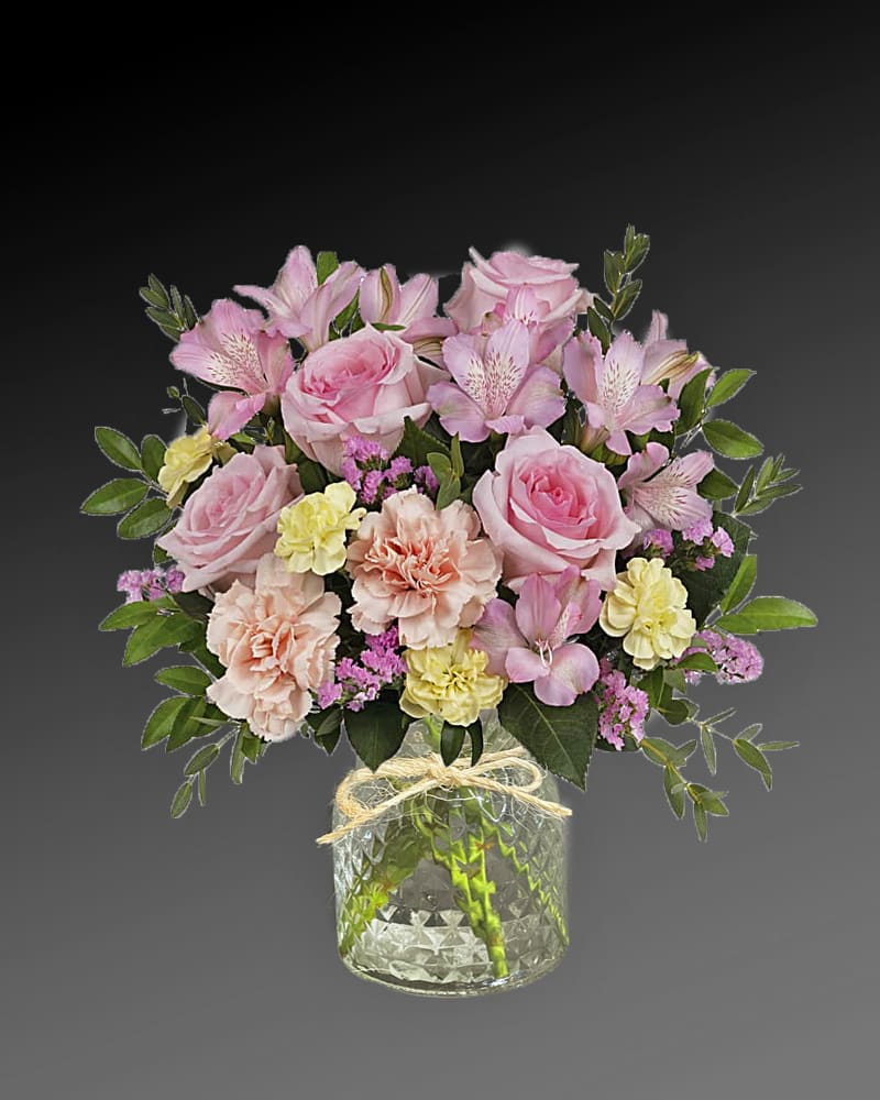 Pink roses and mixed pastel flowers in a clear glass vase