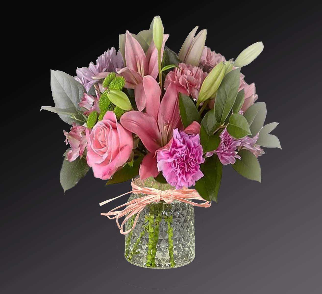 Pink and purple bouquet in a glass vase with a ribbon tie