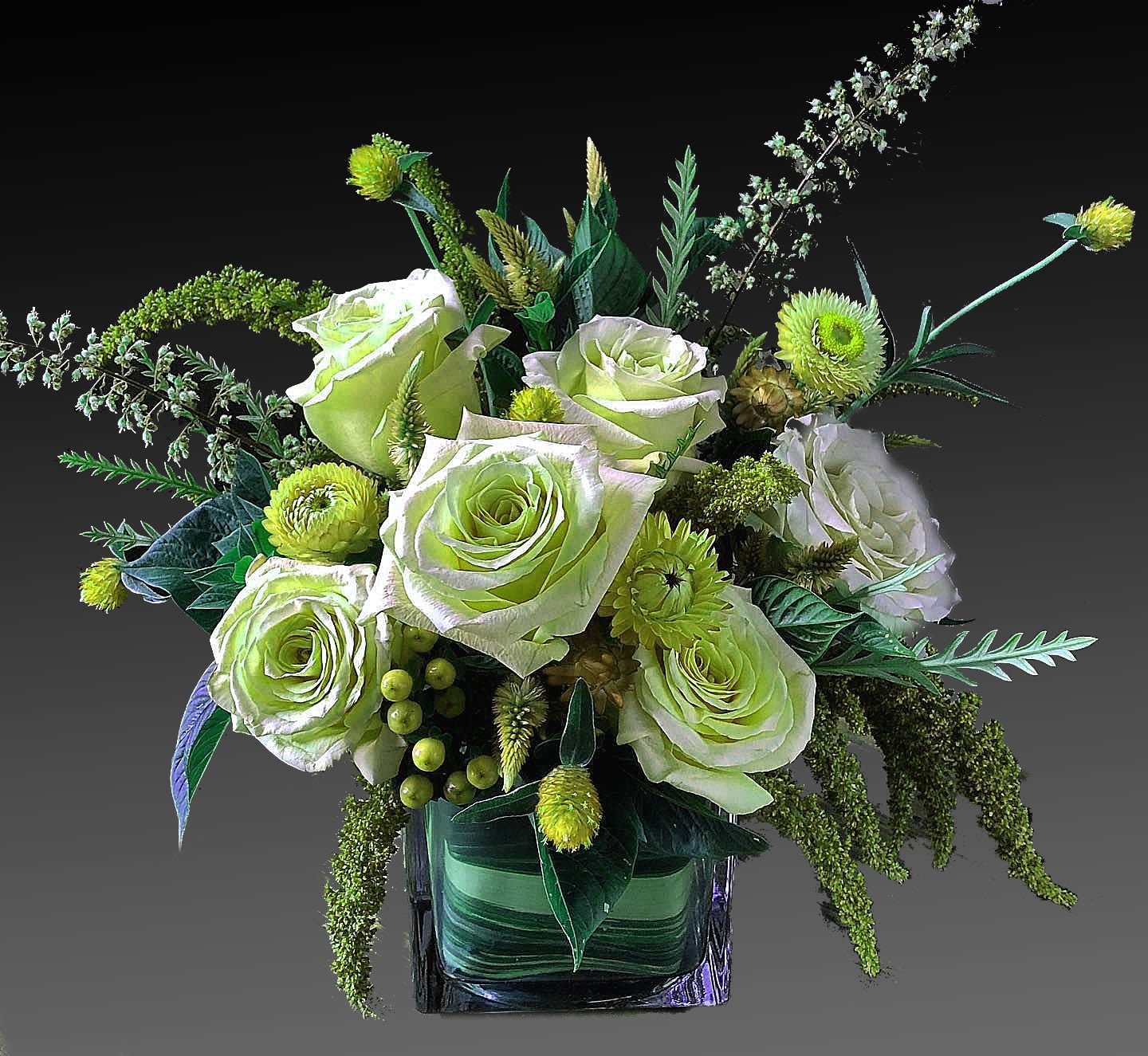 Green and white rose arrangement in a square glass vase