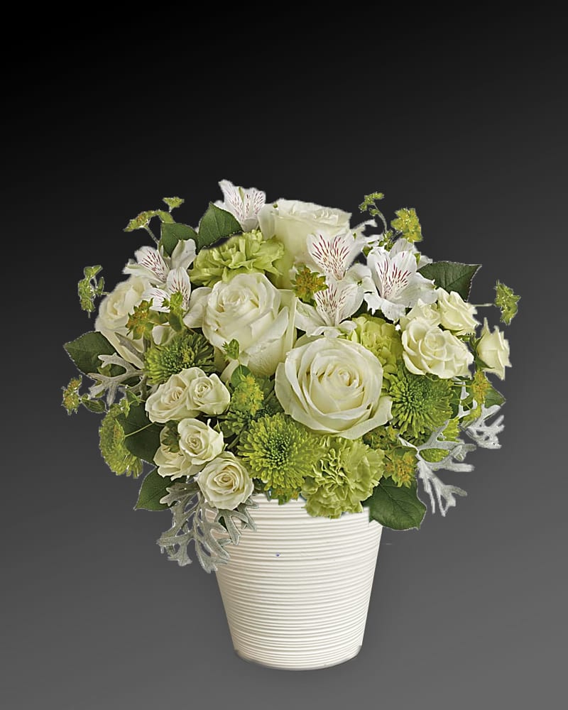 White and green floral arrangement in a ribbed white vase
