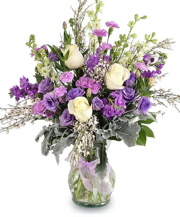 Purple and white bouquet in a clear glass vase with a lavender ribbon