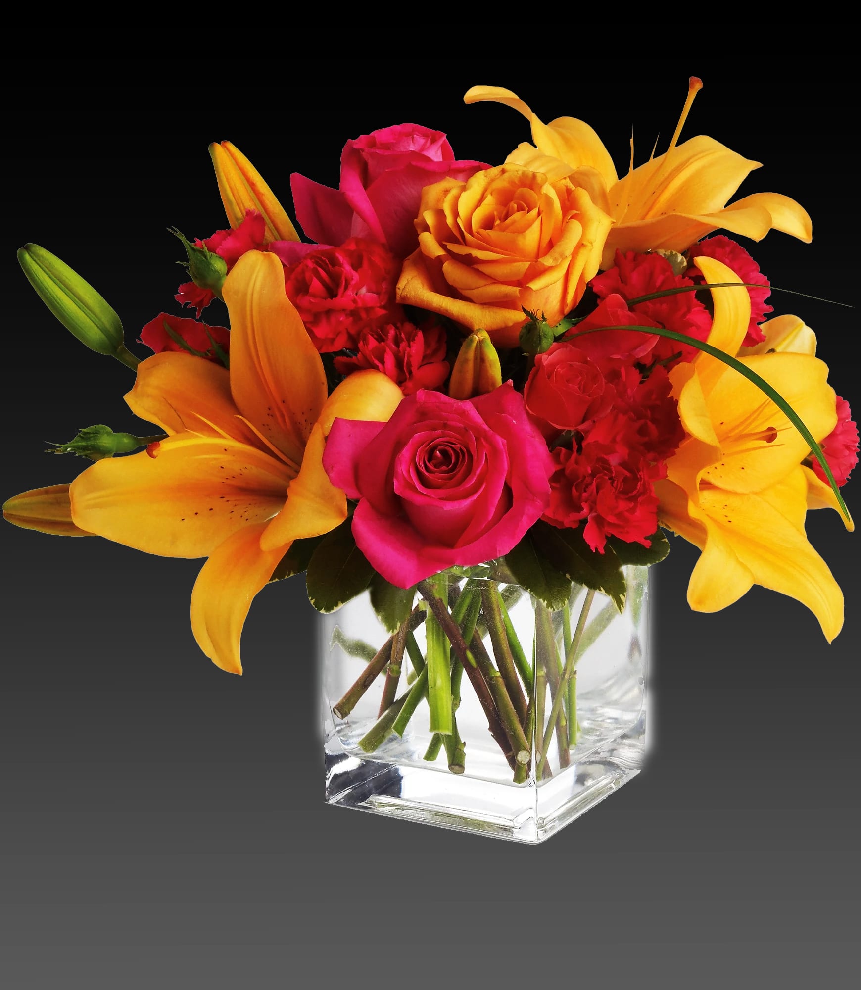 Bouquet of yellow lilies, pink roses, and red carnations in a clear glass vase