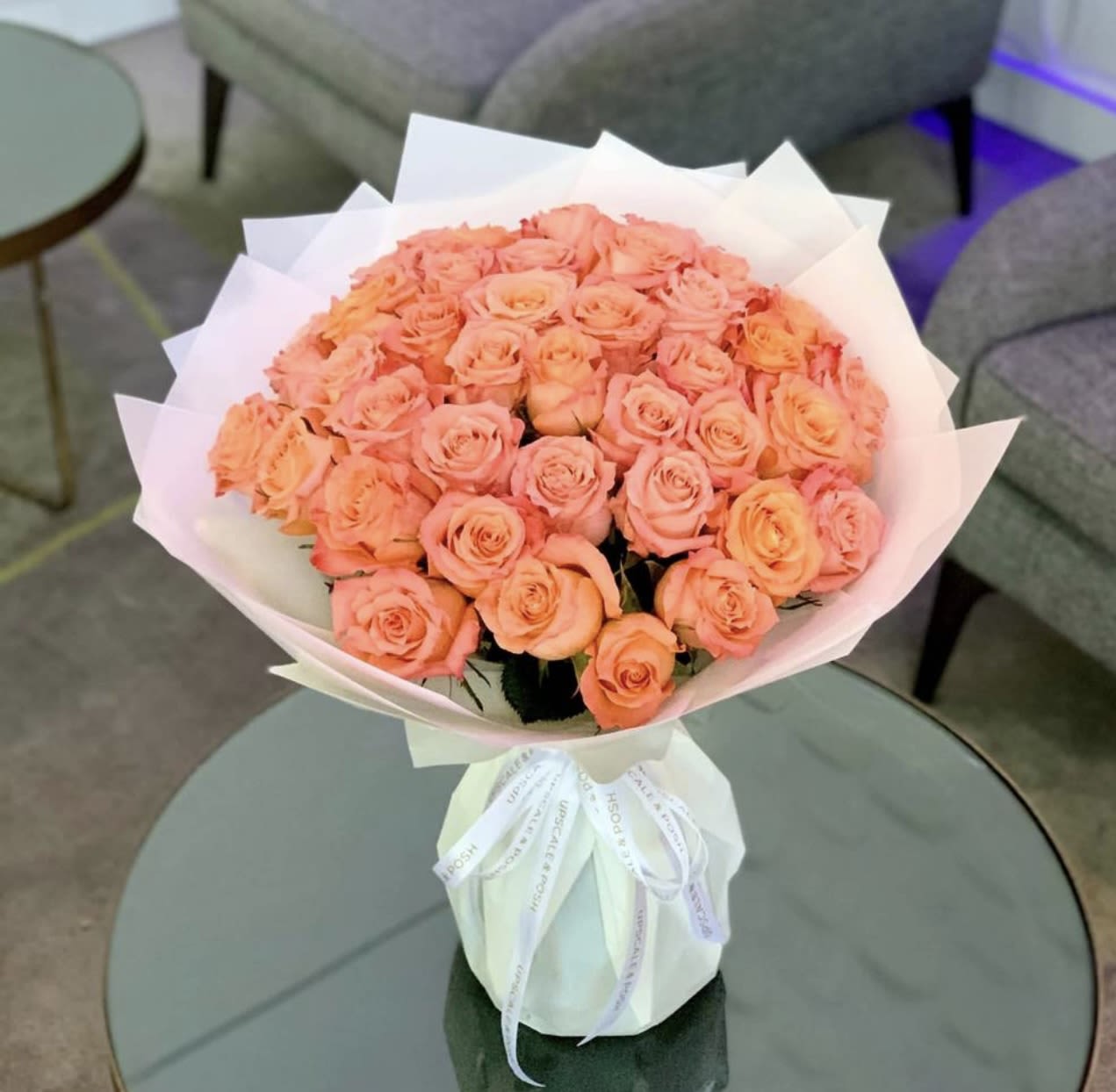Bouquet of peach roses wrapped in white paper with a ribbon