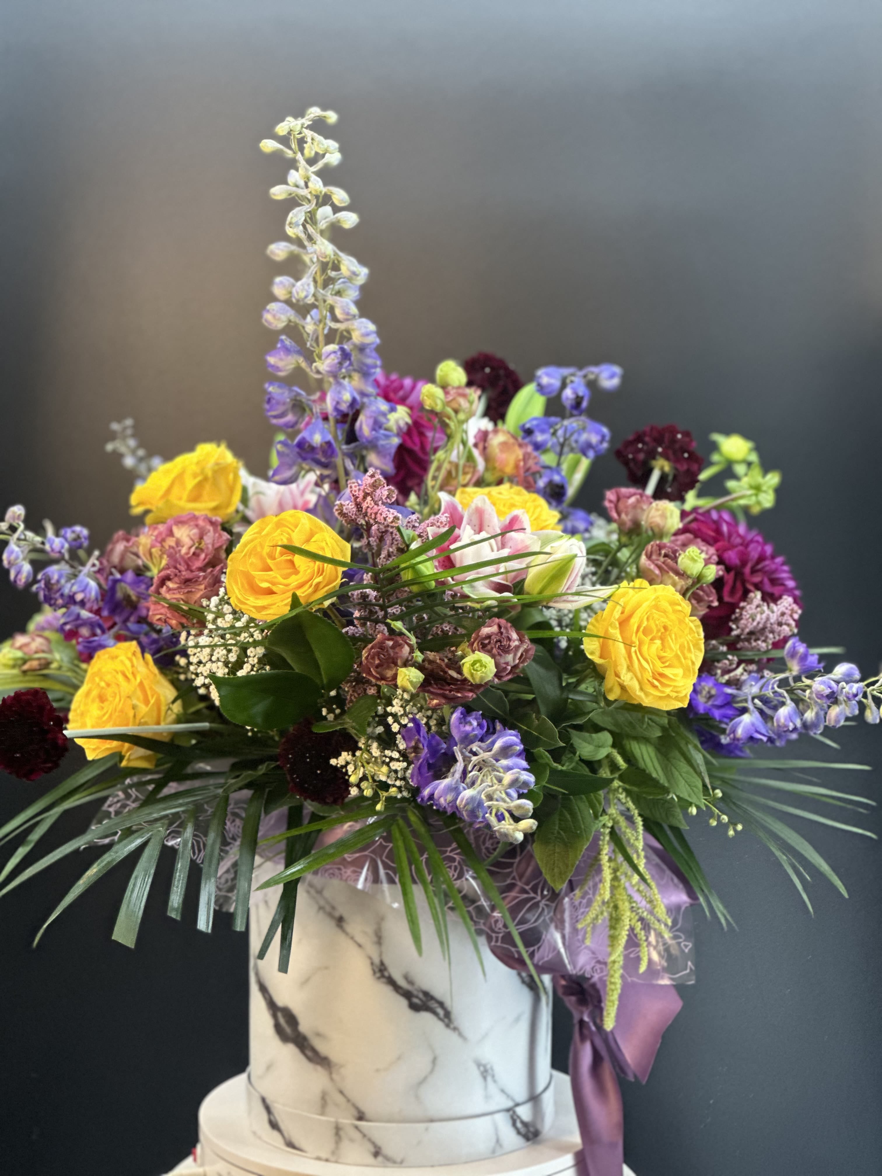 Mixed bouquet in a marble-patterned box with yellow and purple flowers