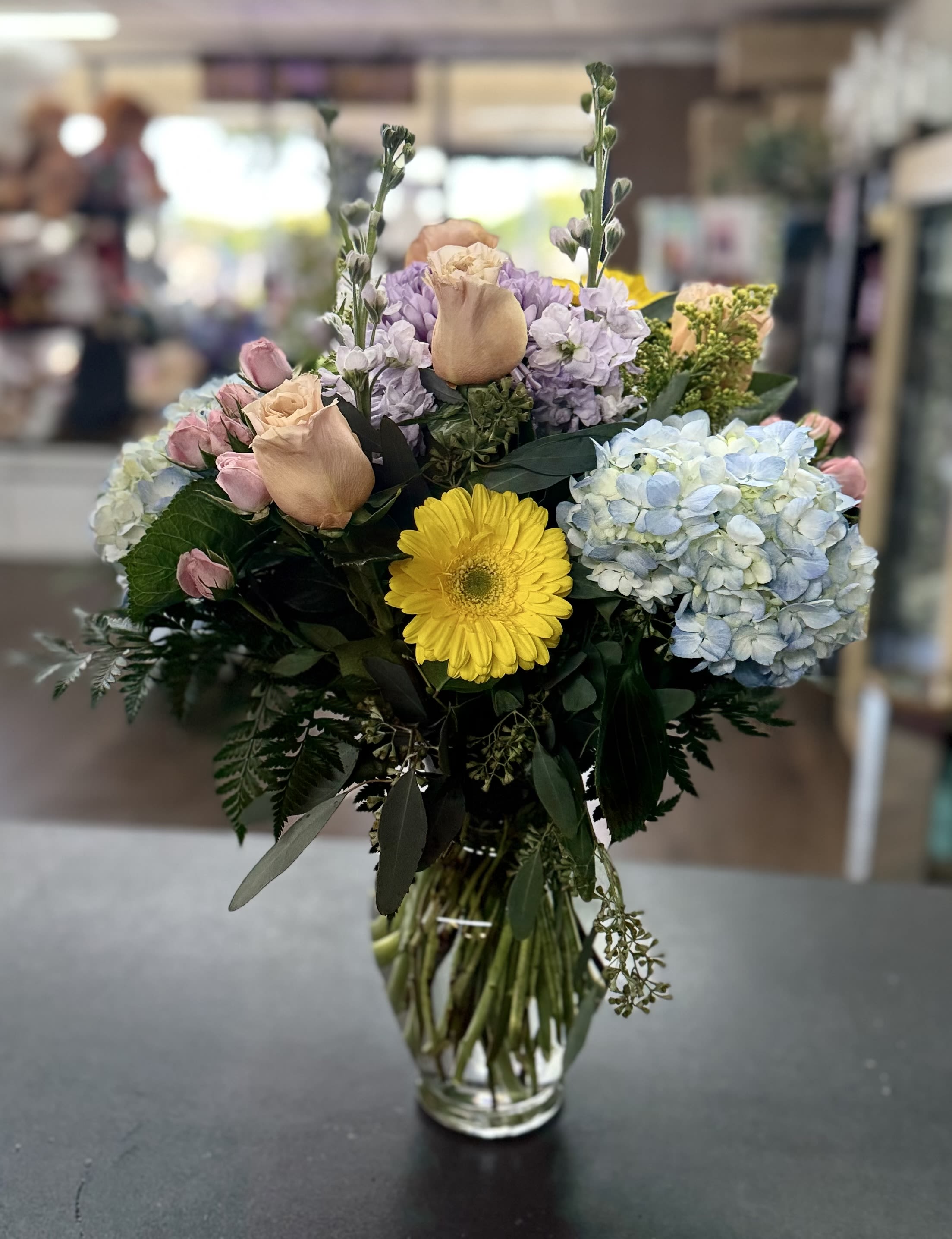 The Queen’s Garden - Clear glass vase bouquet with hydrangeas, roses, gerbera daisies and spray roses in mixed pastels