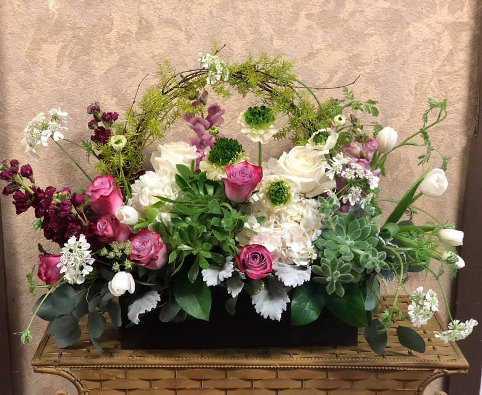 Mixed floral arrangement with pink and white roses in a low black container