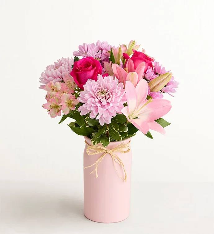 Mother’s Embrace 2 - Bright pink roses and pale pink lilies give this Mother's Embrace 2 arrangement a joyful, romantic presence-perfect as a birthday bouquet, anniversary flowers, or a thoughtful "thinking of you" gift for Mom. The combination of saturated magenta roses, blush lilies, and soft lavender chrysanthemums and daisies reads feminine and fresh, while the taller snapdragon spikes add graceful height so the recipient feels seen and celebrated.