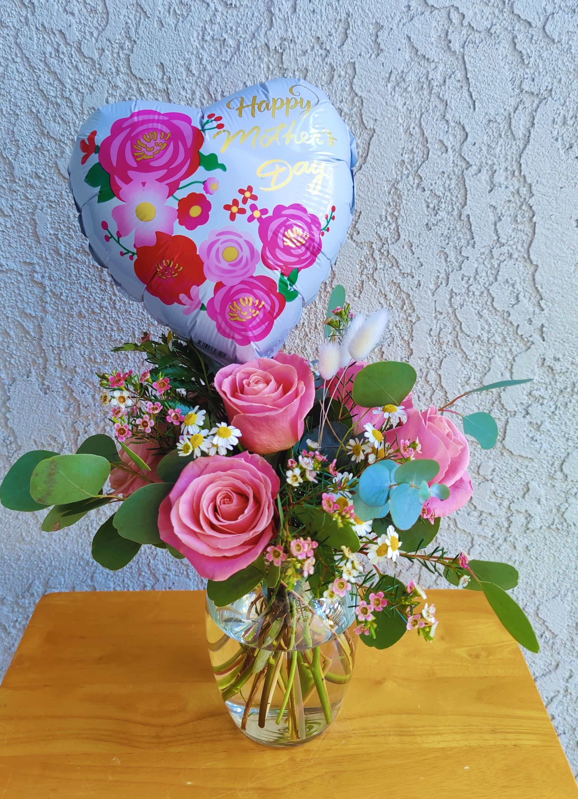 " Happy Mother's Day  " Flowers  - Celebrate mother's Day with this beautiful rose arrangement; it is designed with premium Hermosa roses, seasonal foliage, ornamental chamomile and Wax flowers. It's accented with a mother's day balloon. Size is small  It includes a pretty clear glass vase. 