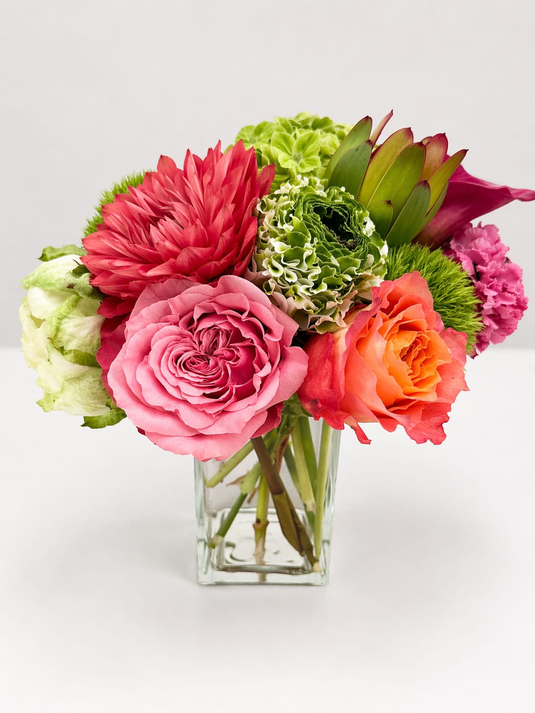 Modern Muse - A striking composition of layered pinks, vibrant coral, and sculptural greens, Modern Muse feels both artful and alive—like a moment thoughtfully gathered and beautifully composed.  Designed for the mom whose presence inspires, grounds, and elevates everything around her, this arrangement reflects a kind of beauty that is confident, nuanced, and entirely her own.  Created not just to be seen, but to be felt, Modern Muse is an expression of appreciation that lingers—capturing the quiet power and lasting impression she brings into your life.
