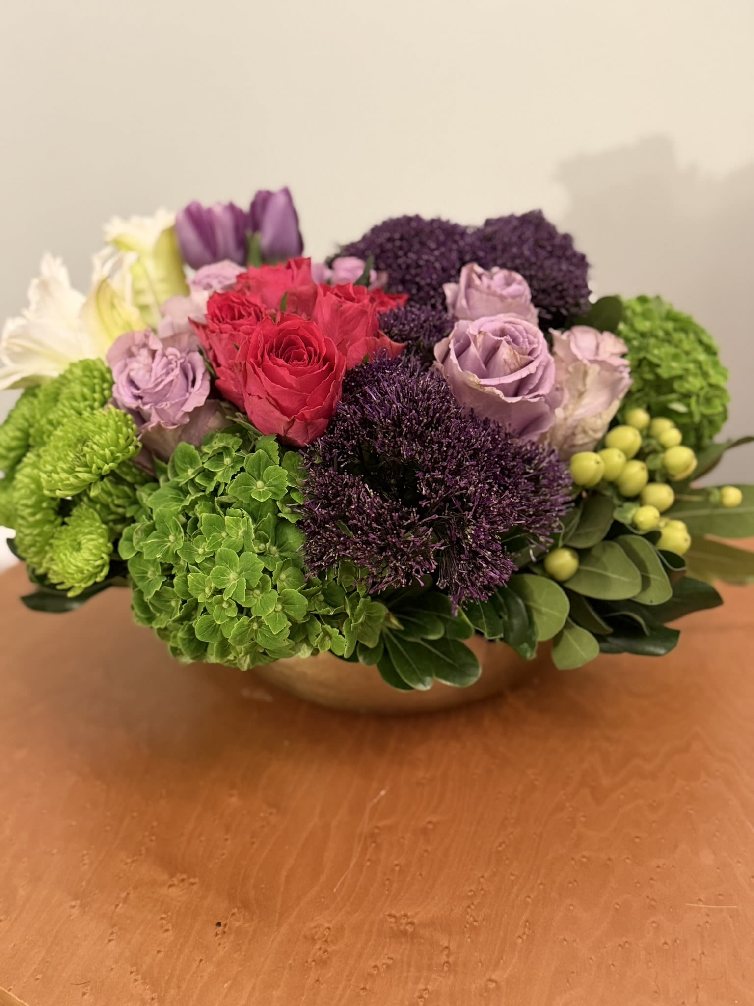 Mixed bouquet of roses, hydrangeas, and green blooms in a low bowl vase