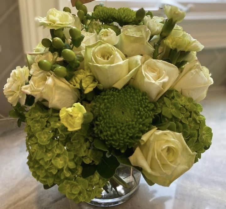 Cream roses and green hydrangeas arranged in a clear glass vase