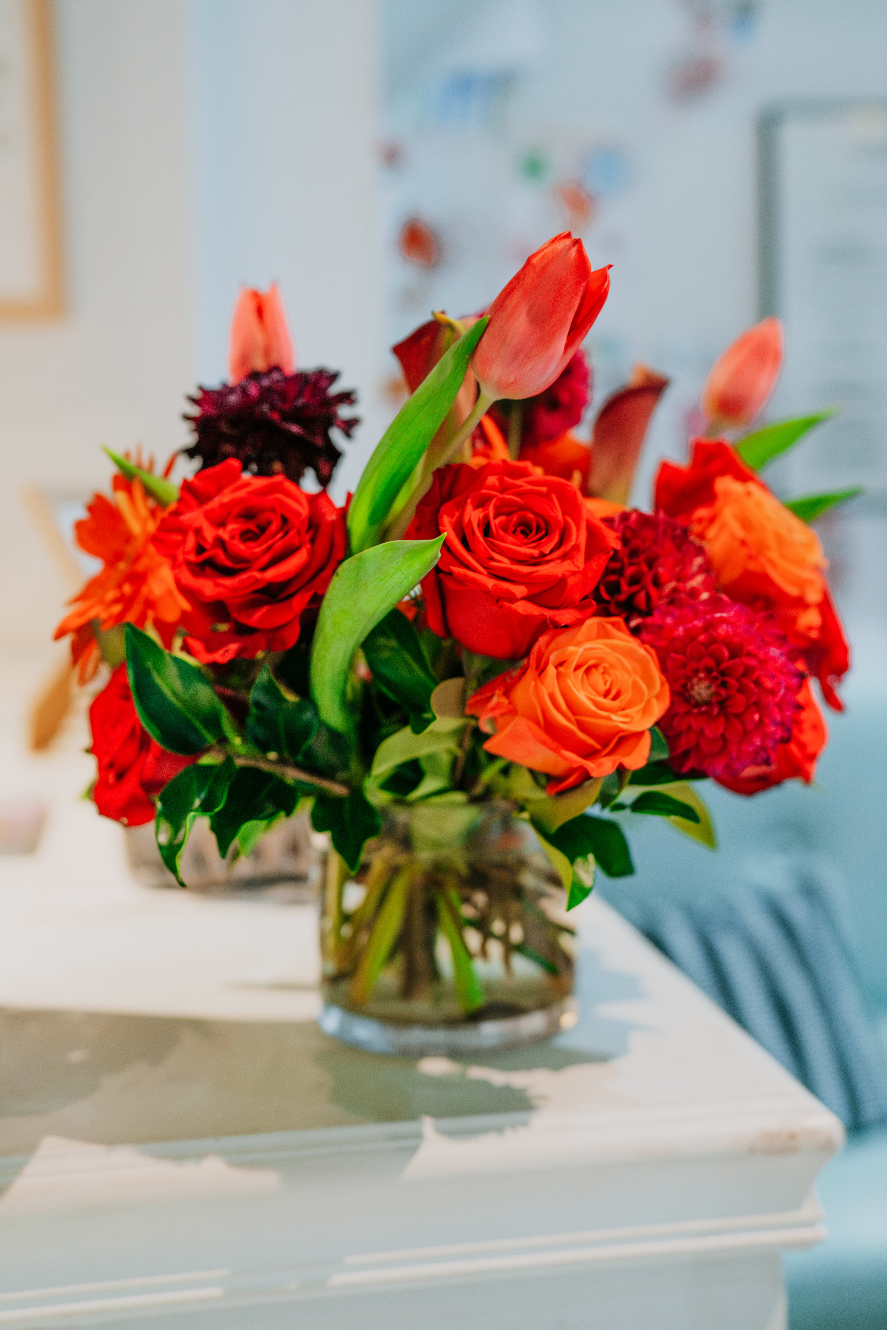 Red and orange flower arrangement in a clear glass vase
