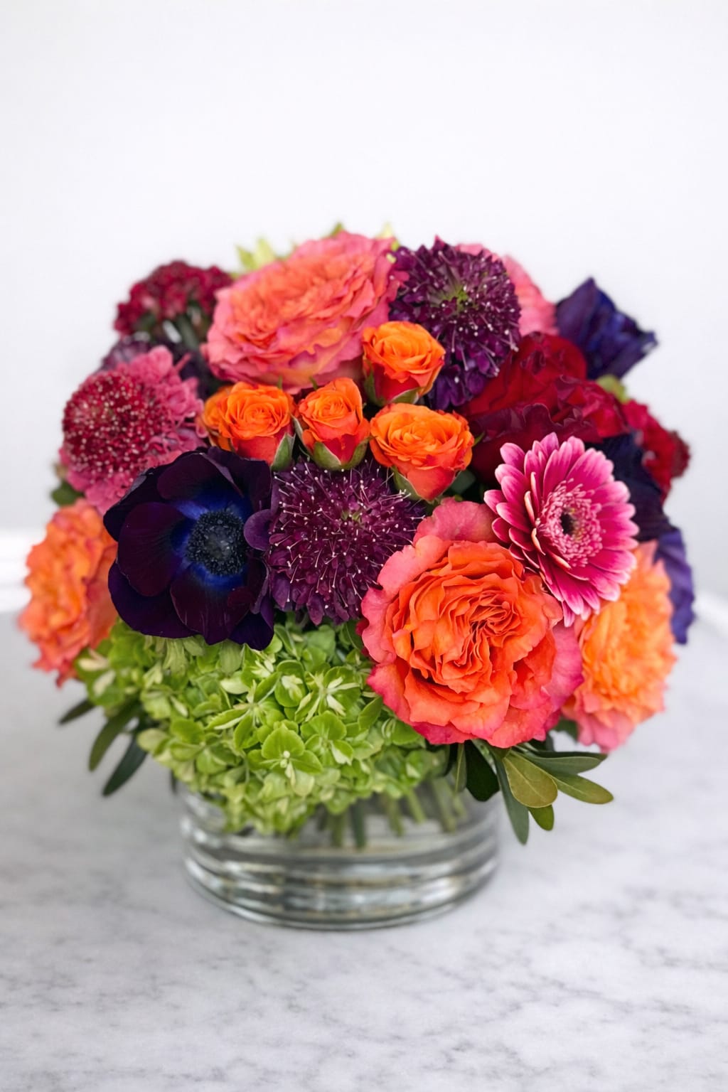 Colorful bouquet of roses, gerbera daisies, and hydrangeas in a glass vase
