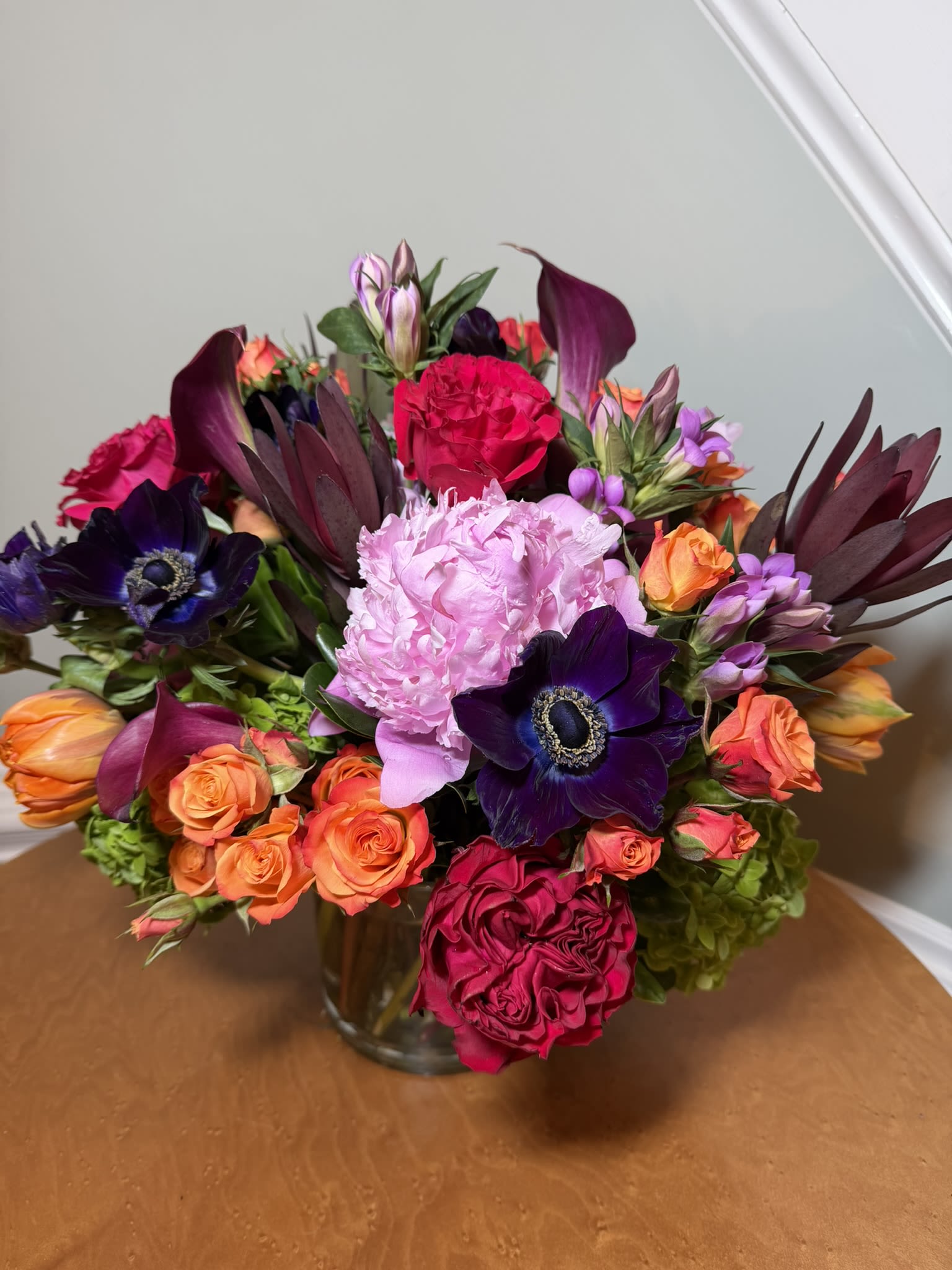 Mixed bouquet of pink, orange, and purple flowers in a glass vase