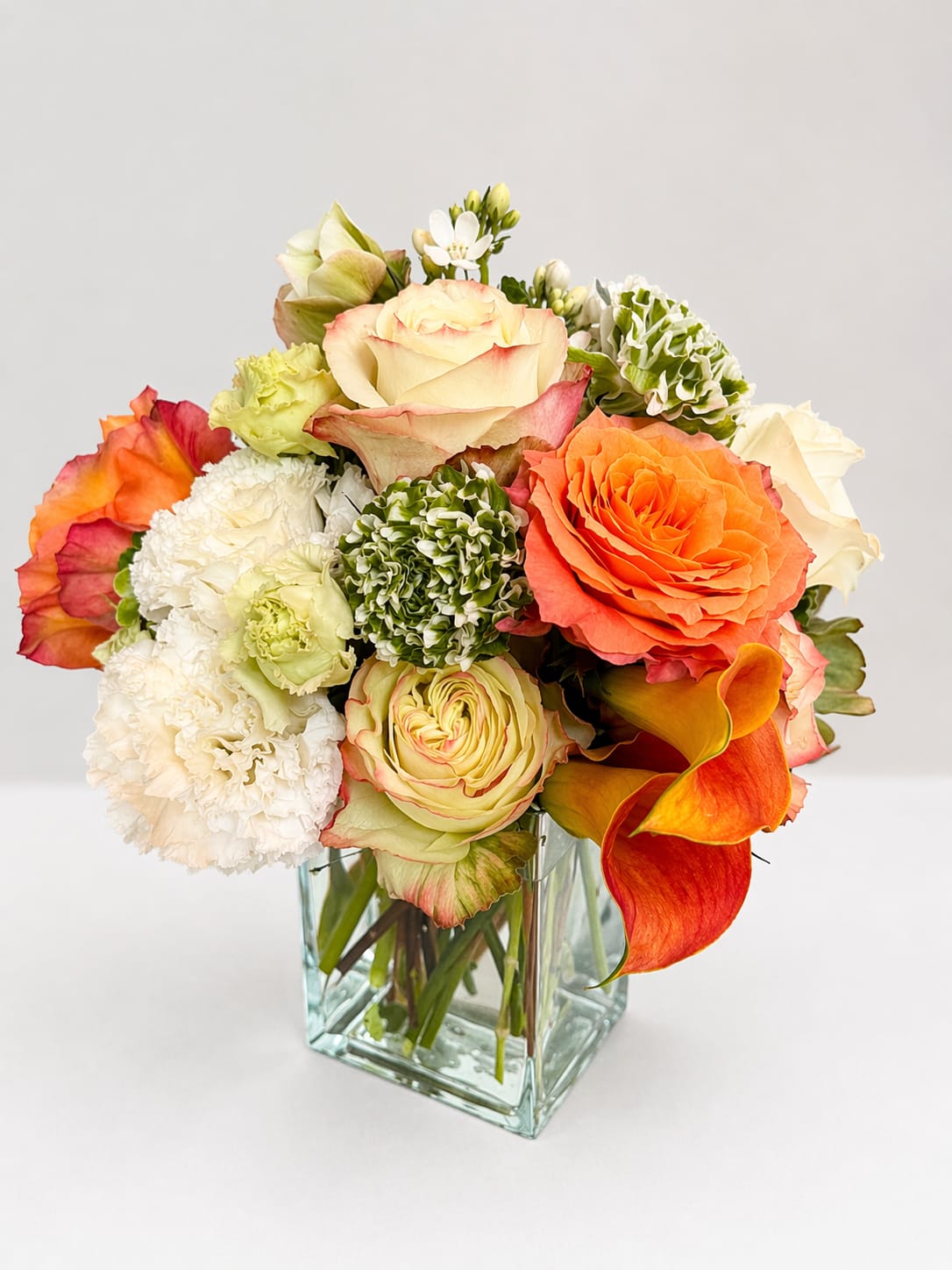 Quiet Light - A luminous composition of soft creams, warm peach, and delicate green textures, Quiet Light feels calm, graceful, and gently radiant—like light settling softly into a room.  Designed for the mom who brings a sense of calm and presence—and a strength that doesn’t need to shout—this arrangement reflects a kind of beauty that doesn’t need to announce itself to be deeply felt.  Quiet Light offers a moment of stillness and appreciation—an expression of love that glows softly and lingers, like the last ray of light at the end of the day.