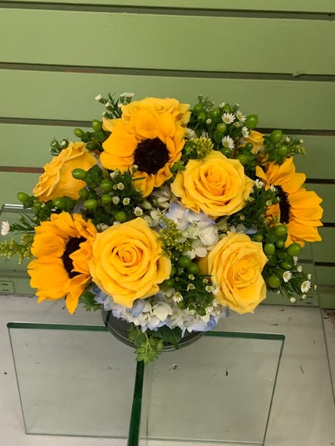 Blue Skies and Sunshine - Classic combination of blue and yellow accented with berries, roses or wisps of beachy grasses and accent flowers. Popular choice year round for many occasions  Wooden box may not be available - we'll substitute a rectangular glass dish NOTE: this combination is available in smaller