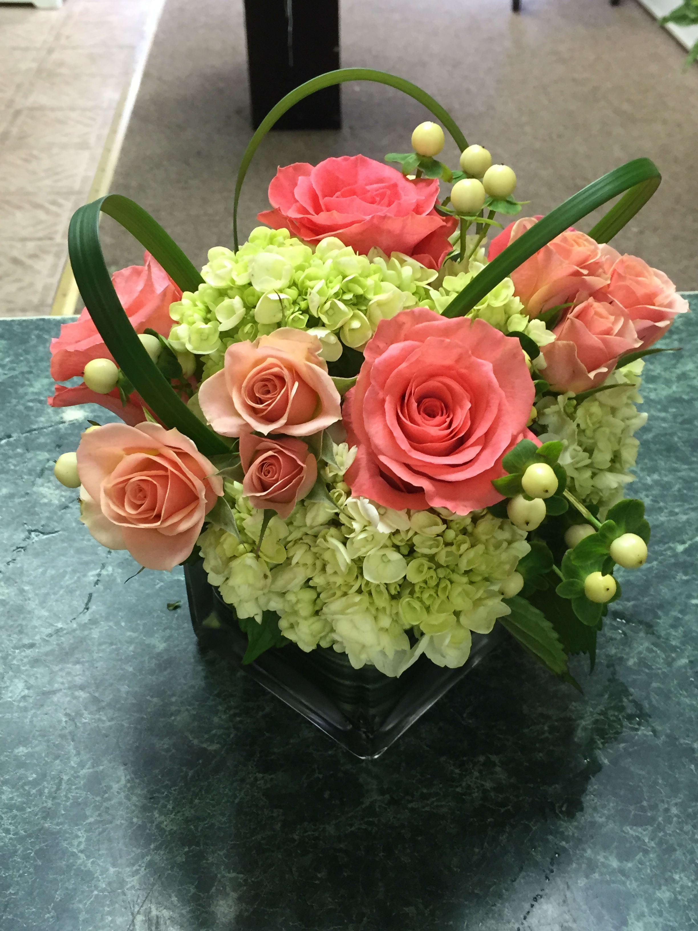 Pelham Manor Peaches - Crisp modern 4" cube design with coral roses, peach spray roses and green hydrangea.Upgraded design descriptions outlined under options.