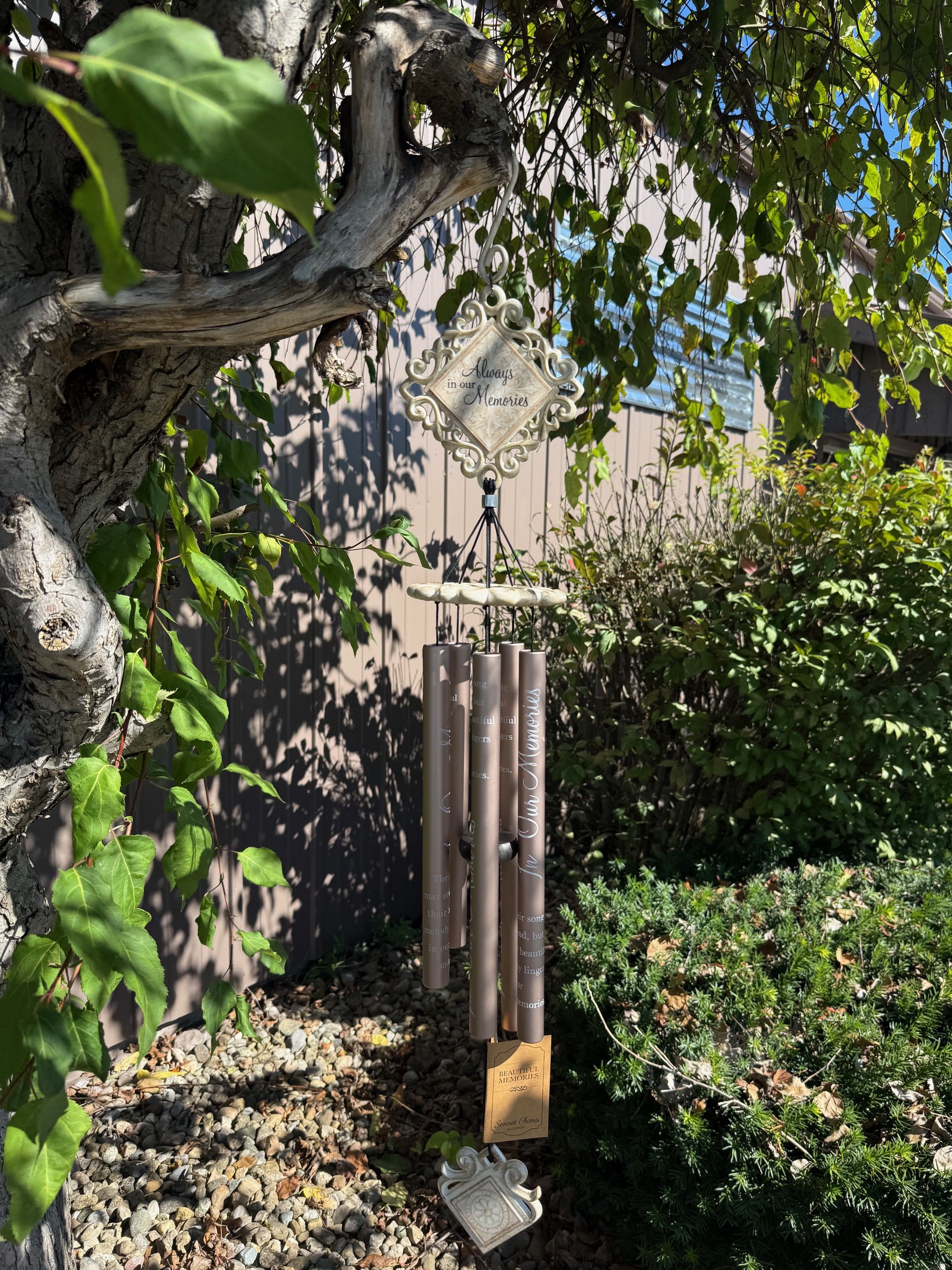 Memorial wind chime hanging from a tree in a garden