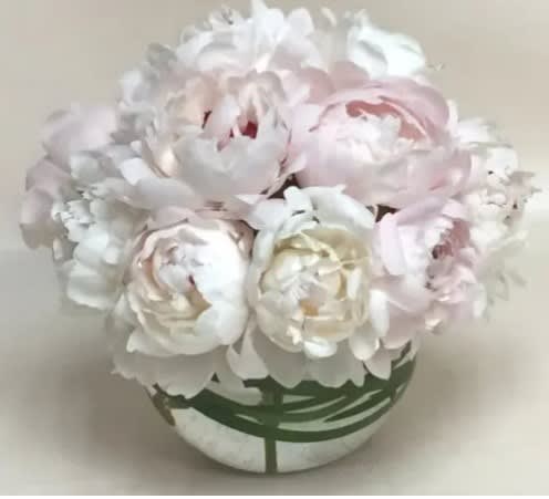 Bouquet of pale pink and white peonies in a round vase