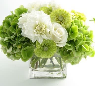 Green and white bouquet in a clear square vase