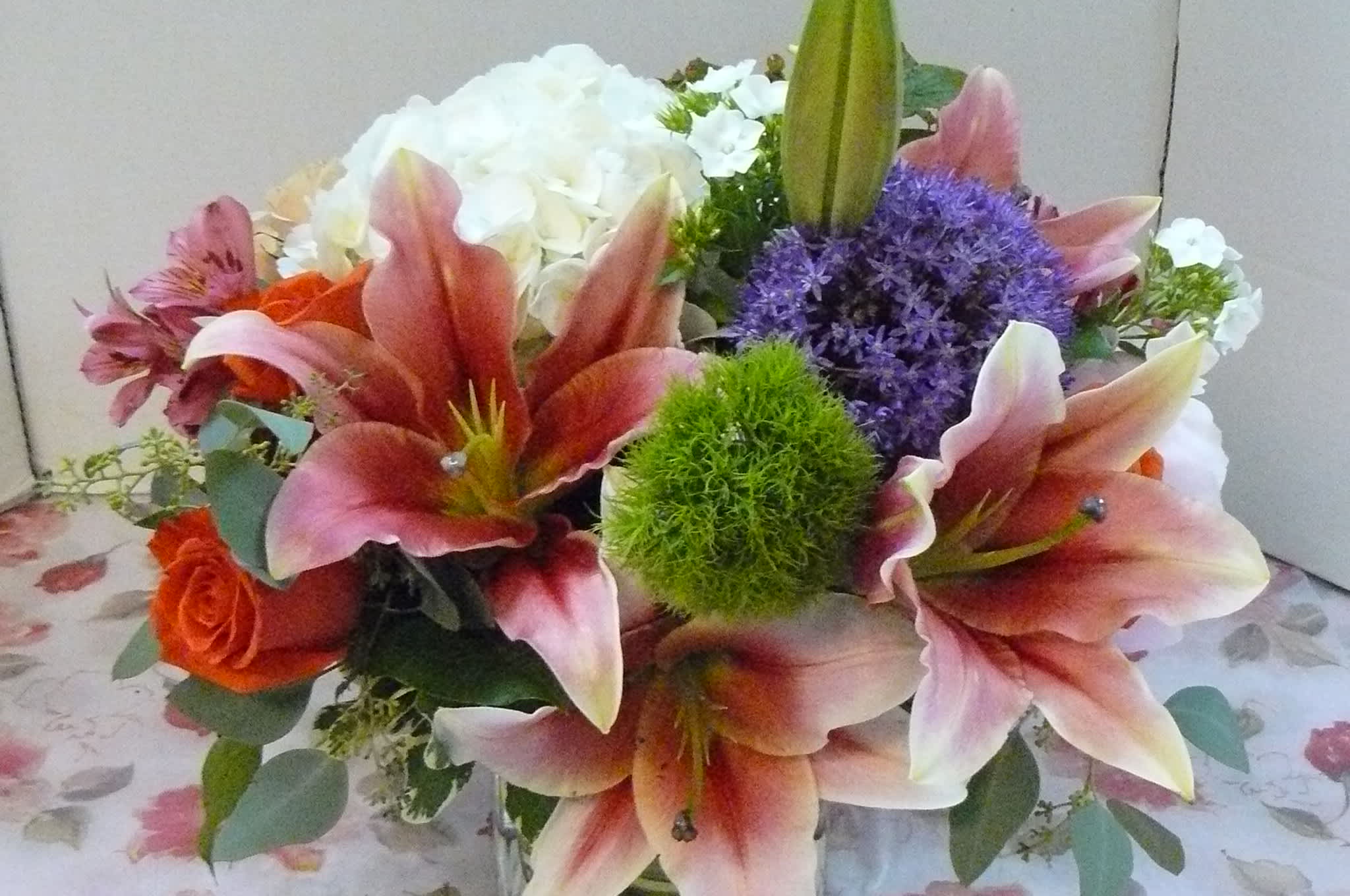 Bouquet of pink lilies, orange roses, and purple flowers