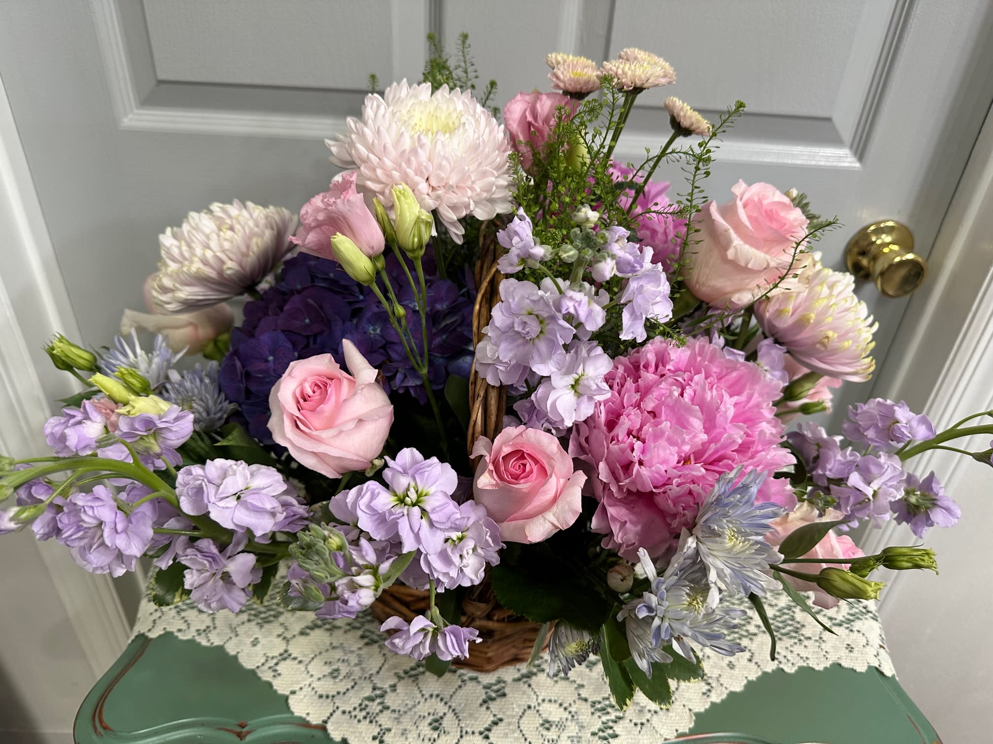 Basket arrangement of pink and lavender flowers with roses and chrysanthemums