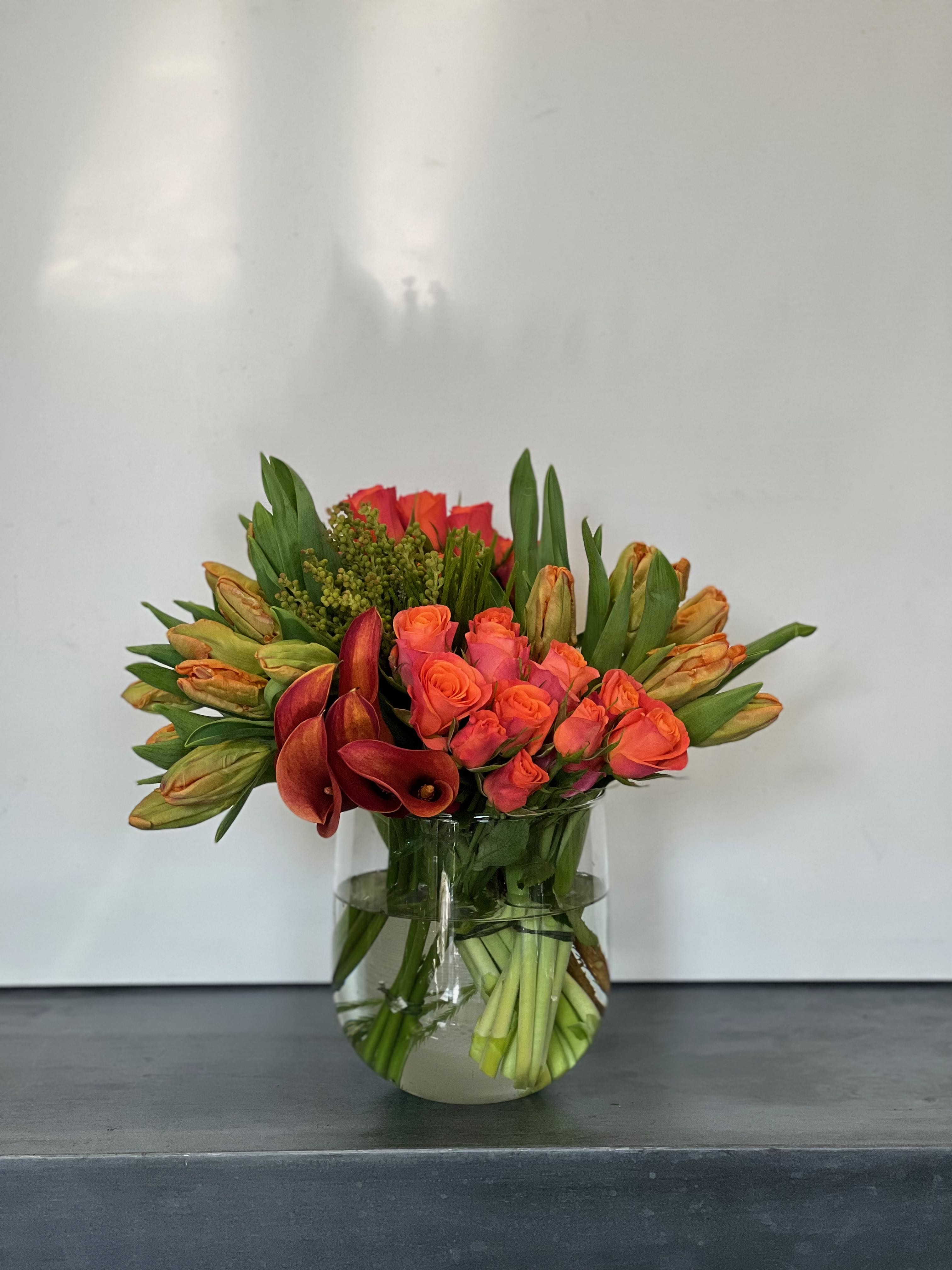 A Summer Sunset - Shades and textures of orange arranged in modern clusters of tulips, roses, calla lily and textures of green.  *Please note that we are doing our best to replicate our designs exactly as shown, but with the  supply chain issues these days we will design as closely as possible.  If something is not available that will change the overall look of the arrangement we will reach out to let you know.