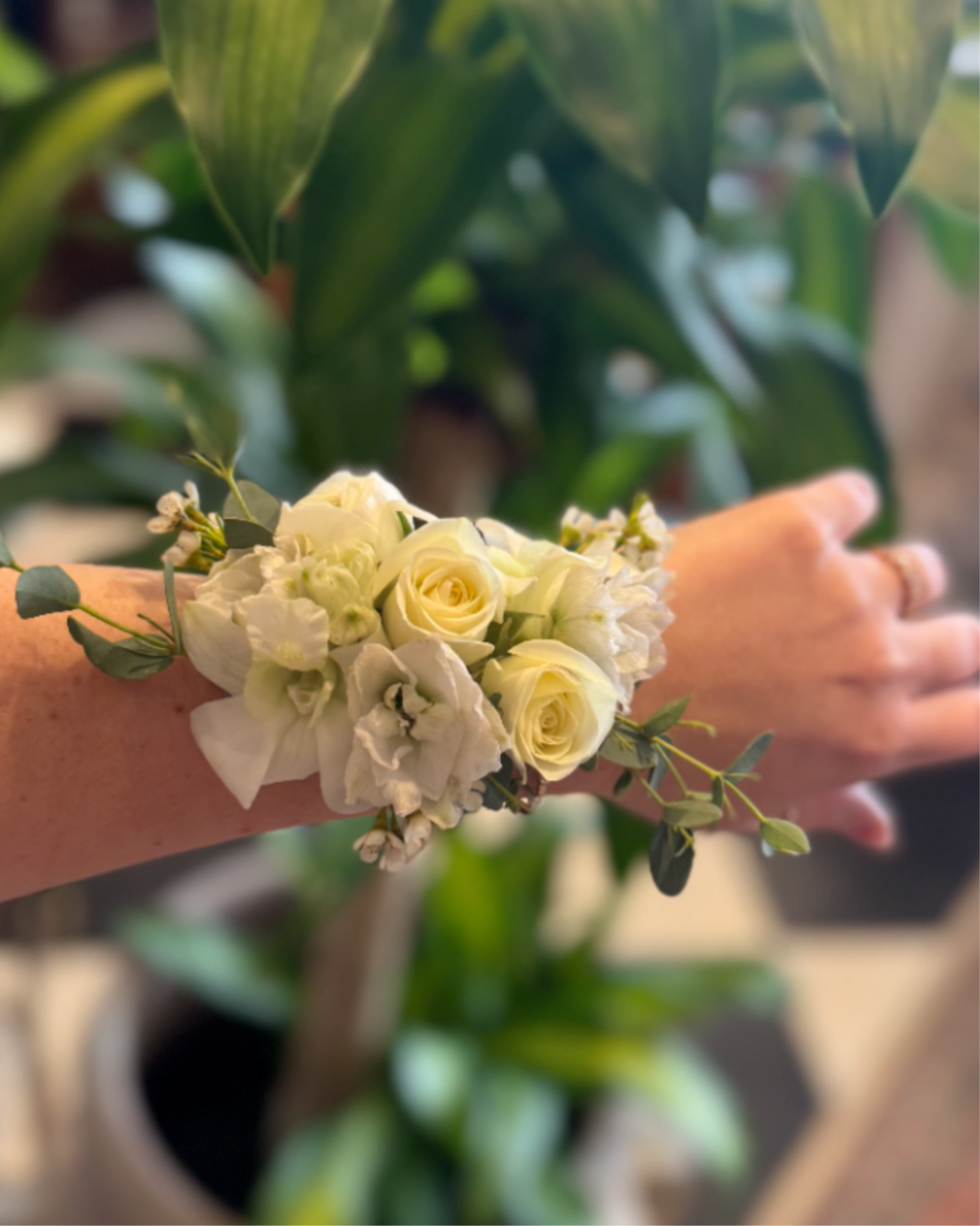 Wrist Corsage  - A beautiful compliment to any dress. We use a combination of blooms and greens arranged on a metal cuff bracelet to achieve a lush, modern look. Example blooms/greens include (but are not limited to) spray roses, ranunculus, orchids, delphinium, mini carnations, wax flower, eucalyptus, myrtle, ruscus. Please specify any color requests in the instructions, otherwise we will make the corsage all white.