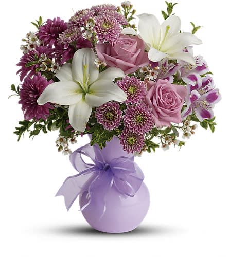 Bouquet of pink roses, white lilies, and purple flowers in a lavender vase
