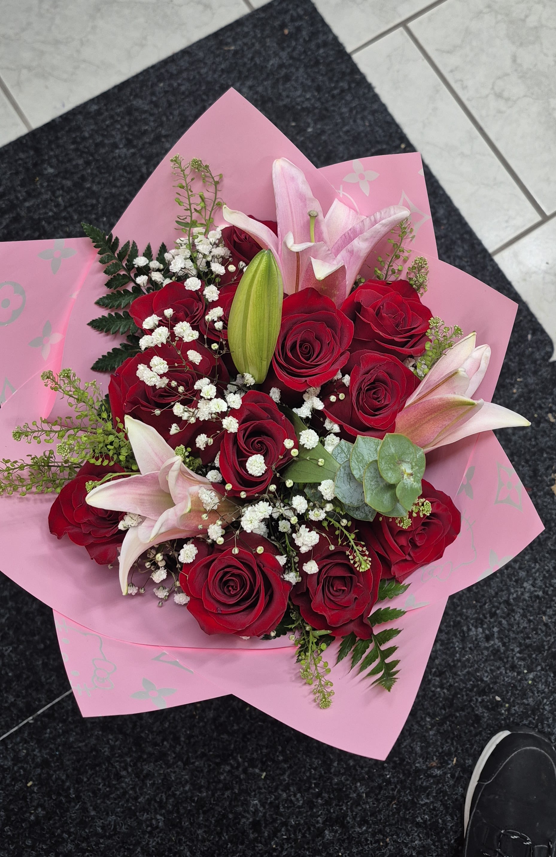 Bouquet of red roses and pink lilies wrapped in pink paper