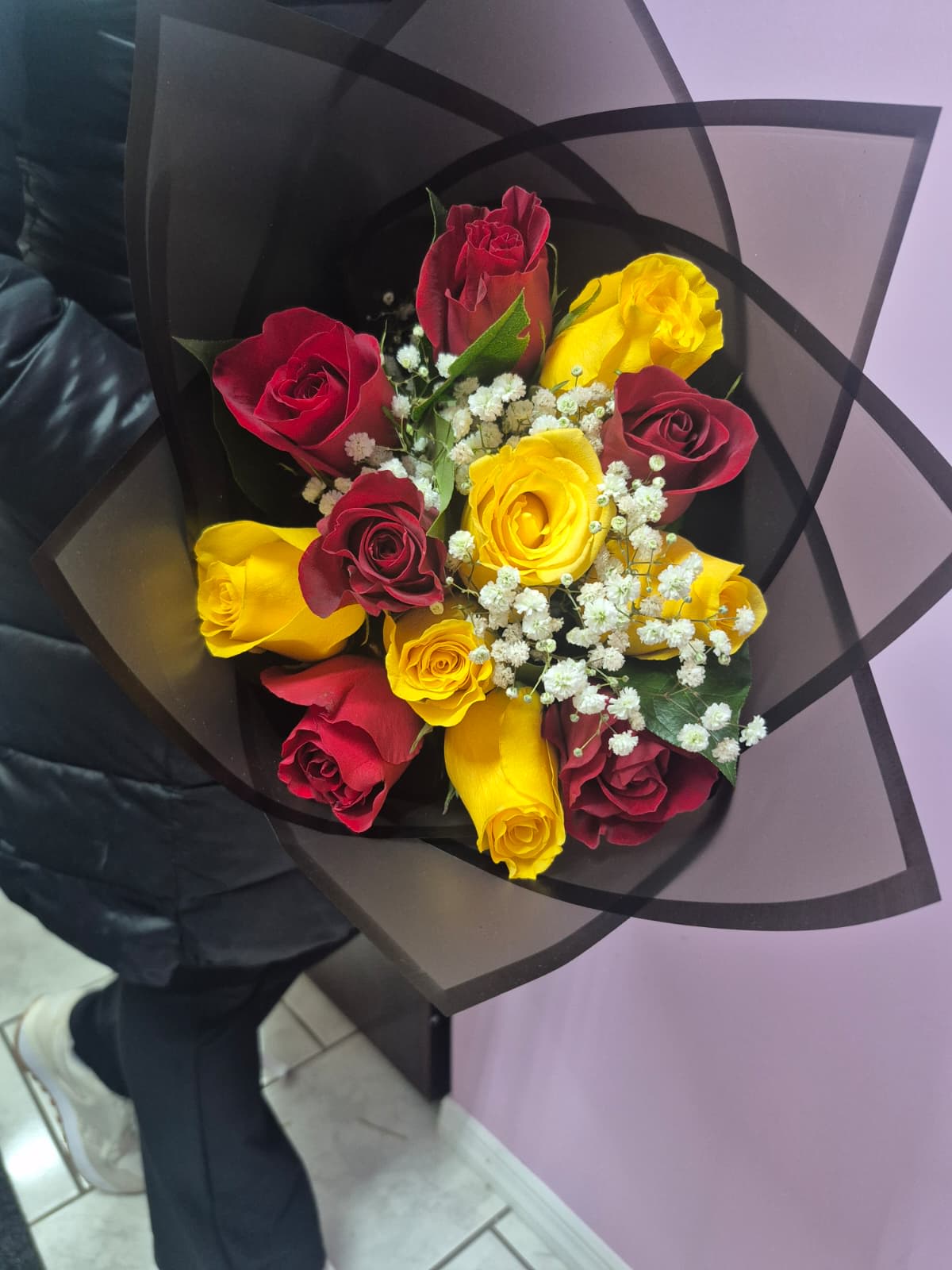 Bouquet of red and yellow roses with white baby's breath in black wrap
