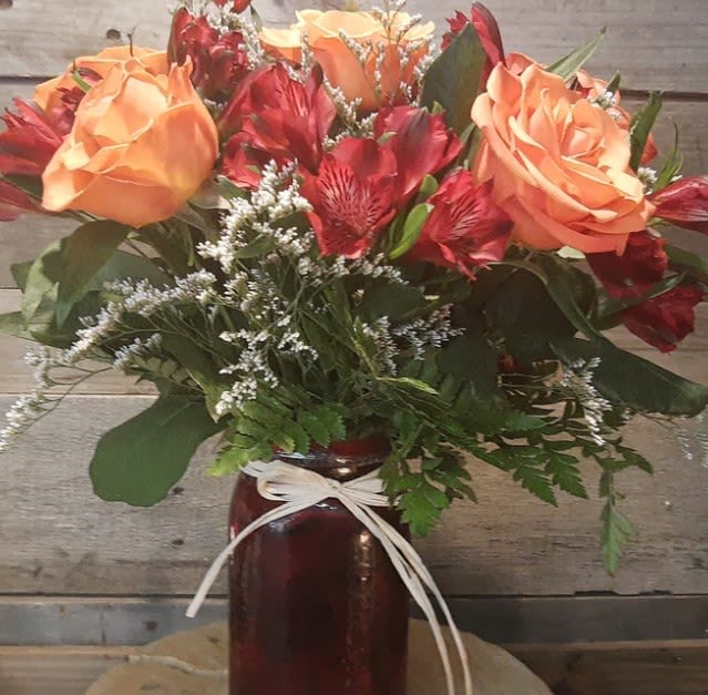 Bouquet of peach roses and red alstroemeria in a dark vase