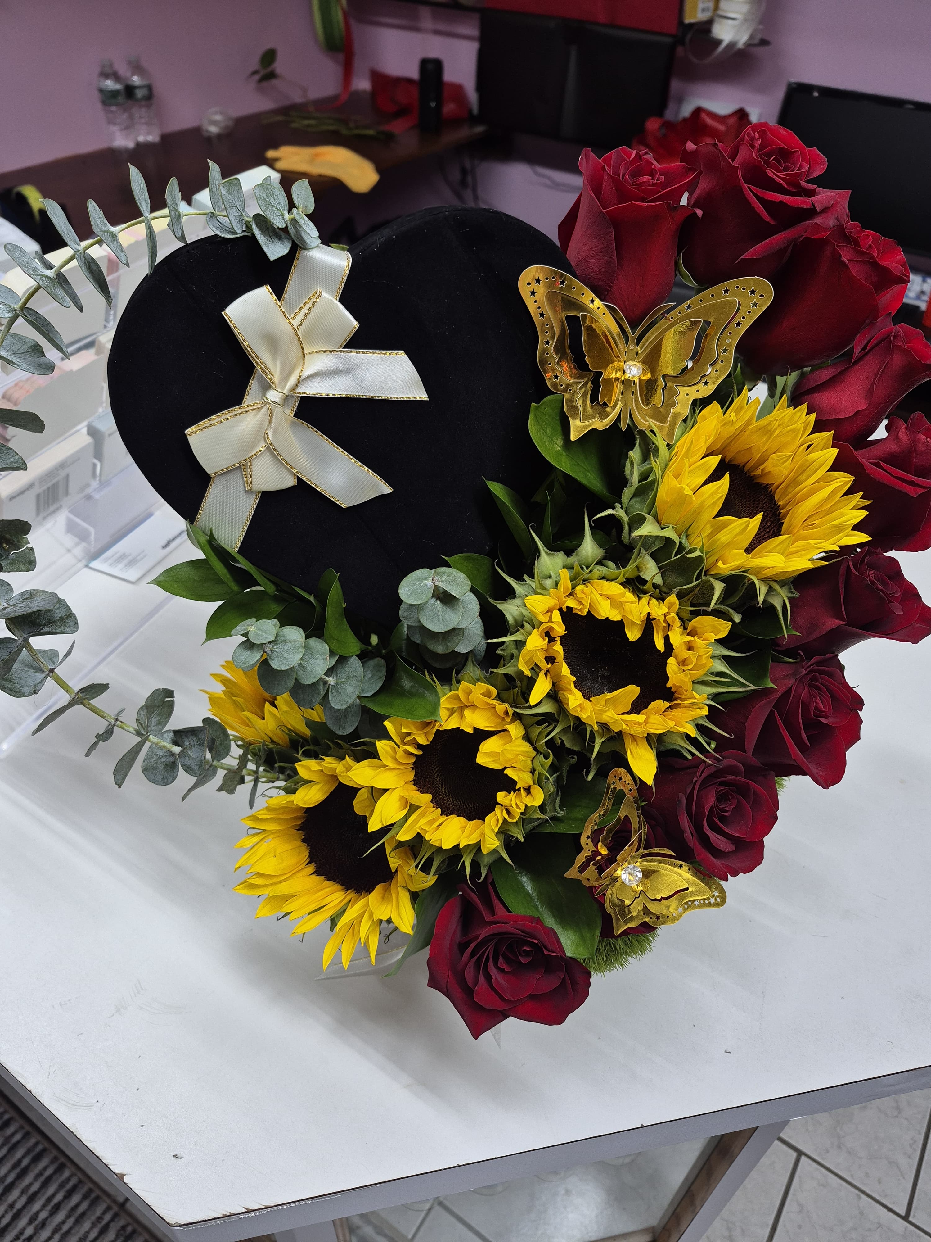 Heart-shaped floral arrangement with red roses and yellow sunflowers