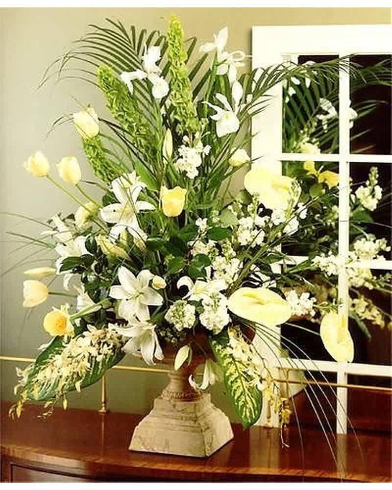 Tall arrangement of white and pale yellow flowers in a stone urn vase