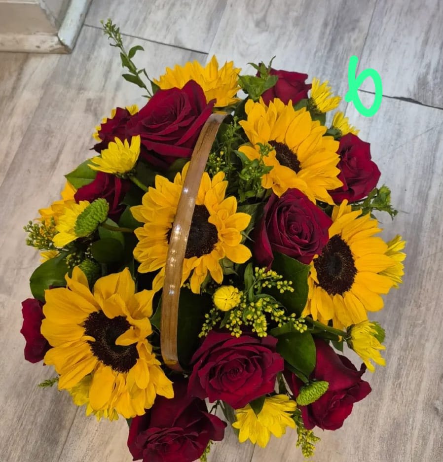 Basket of red roses and yellow sunflowers on a floor.