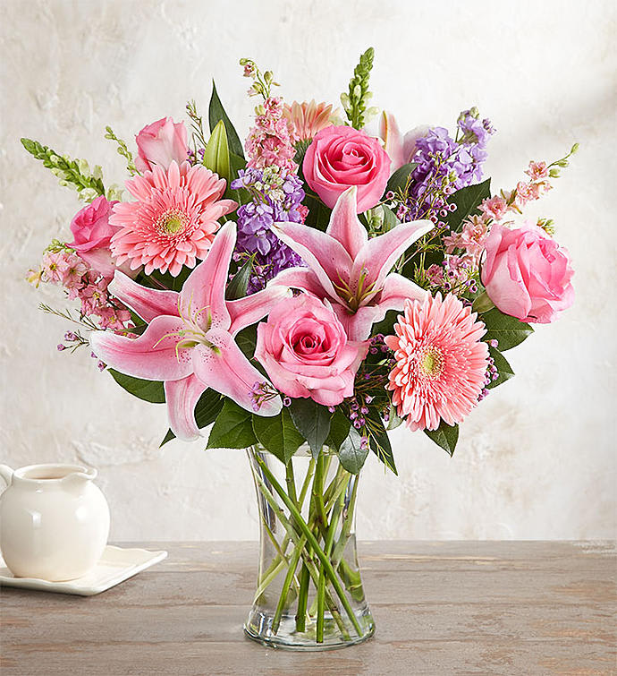 Pink roses, lilies, and gerbera daisies in a clear glass vase