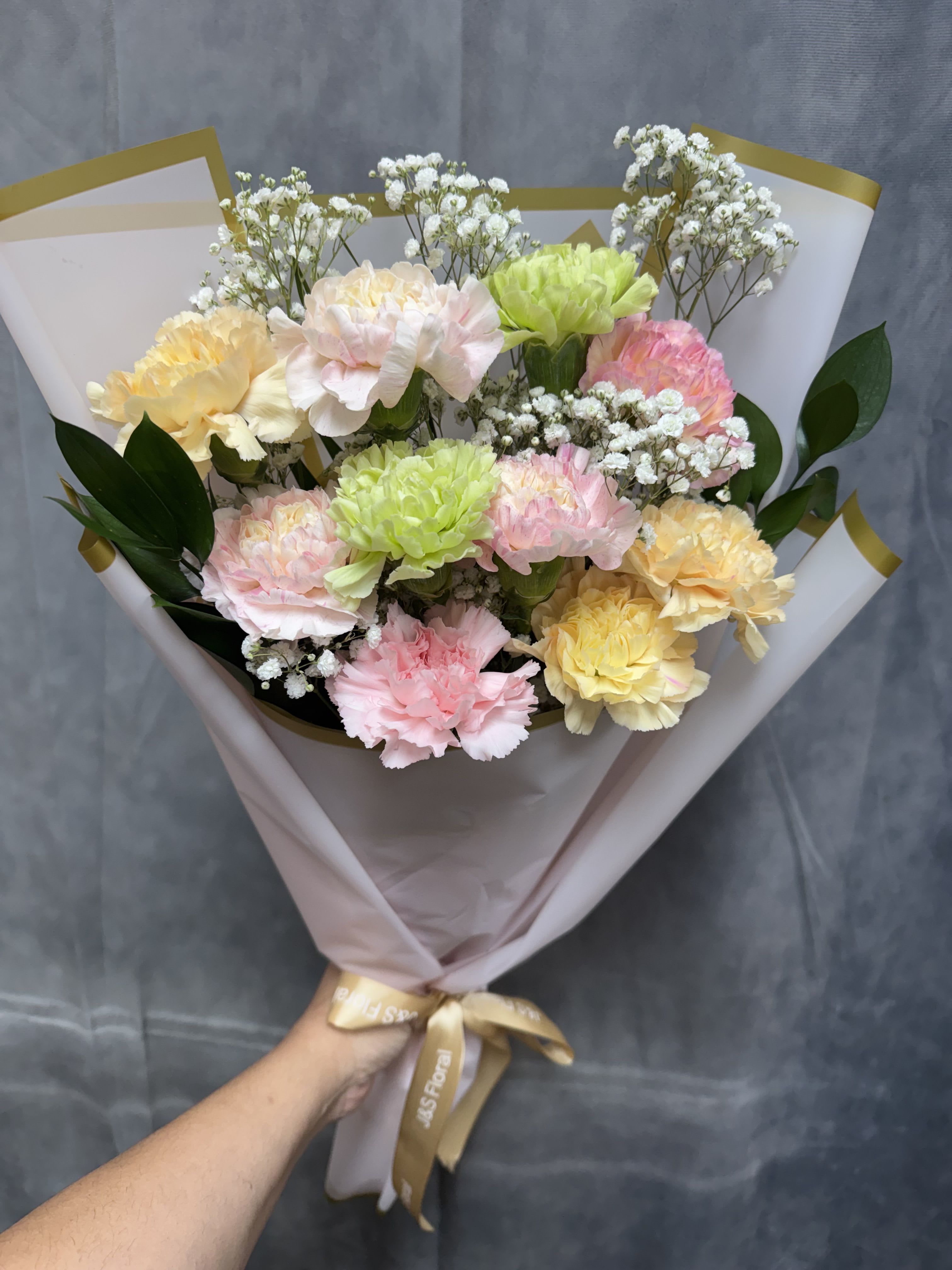 Carnation lovers bouquet  - Soft pastel carnations with white filler, wrapped in paper and satin ribbon for a cheerful, gift-ready spring bouquet.