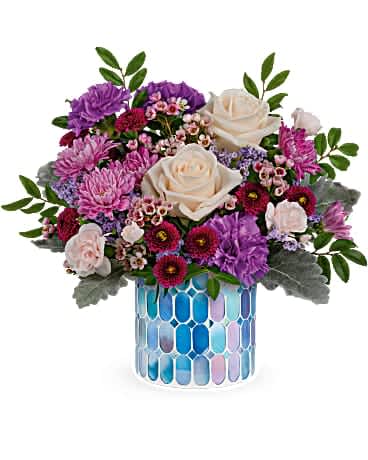 Bouquet of cream roses, purple chrysanthemums, and pink filler flowers in a blue mosaic vase