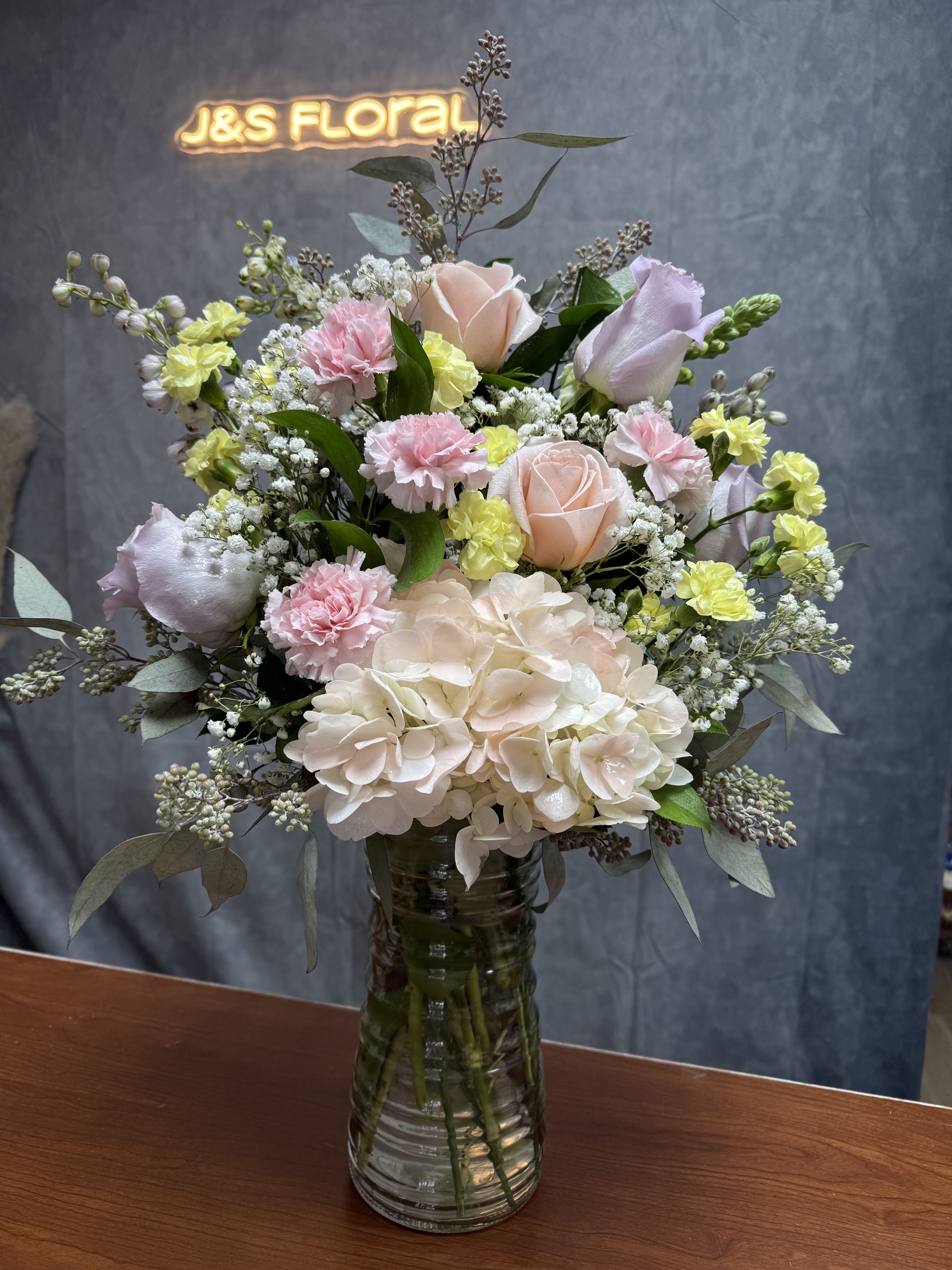 Pastel Beauty Vase - Introducing our new design Pastel Blooms, beautifully arranged with mums, spray roses, mini carnations, delphinium, fillers and greenery. 