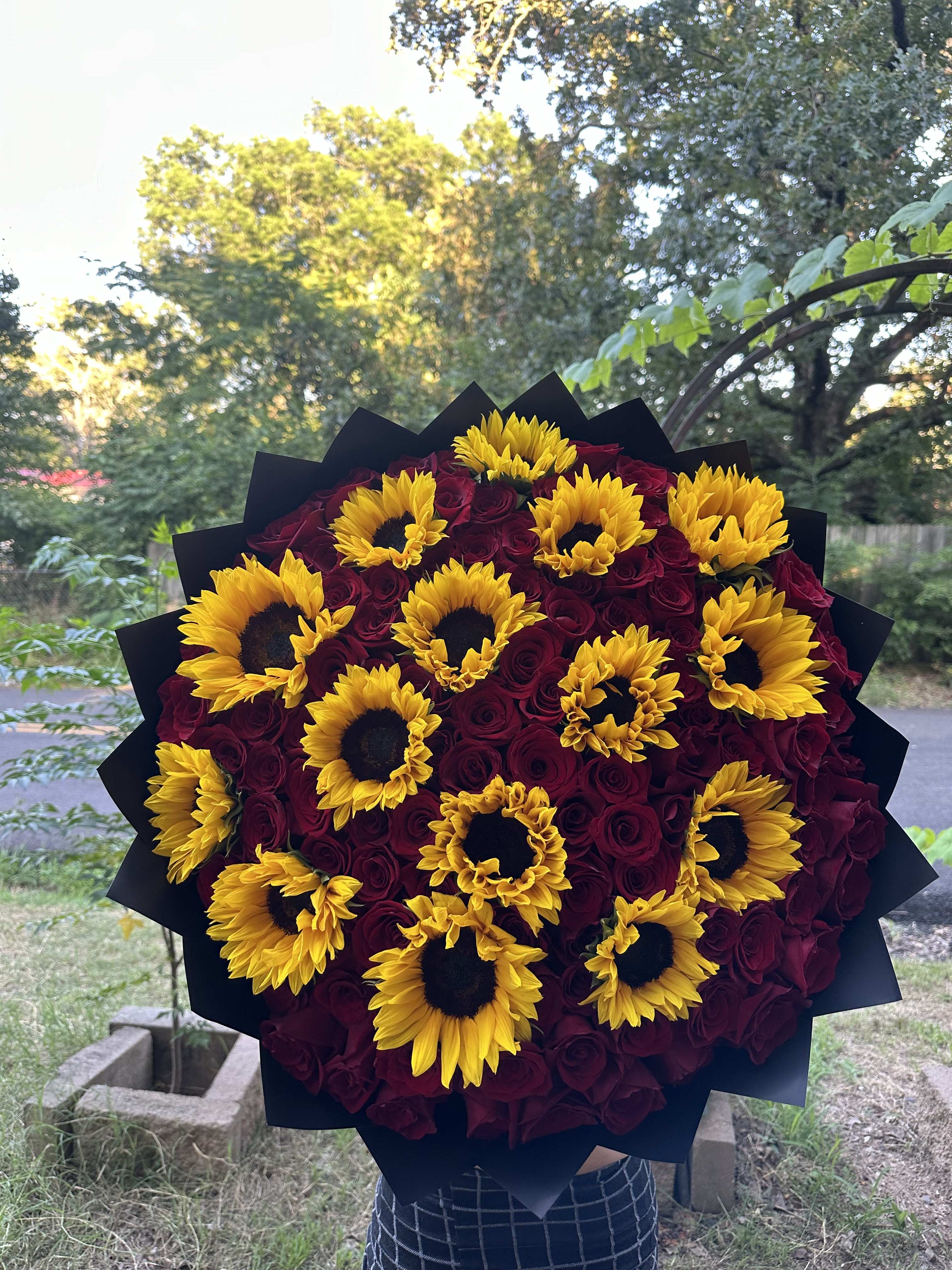 Bouquet of yellow sunflowers and deep red roses wrapped in black paper