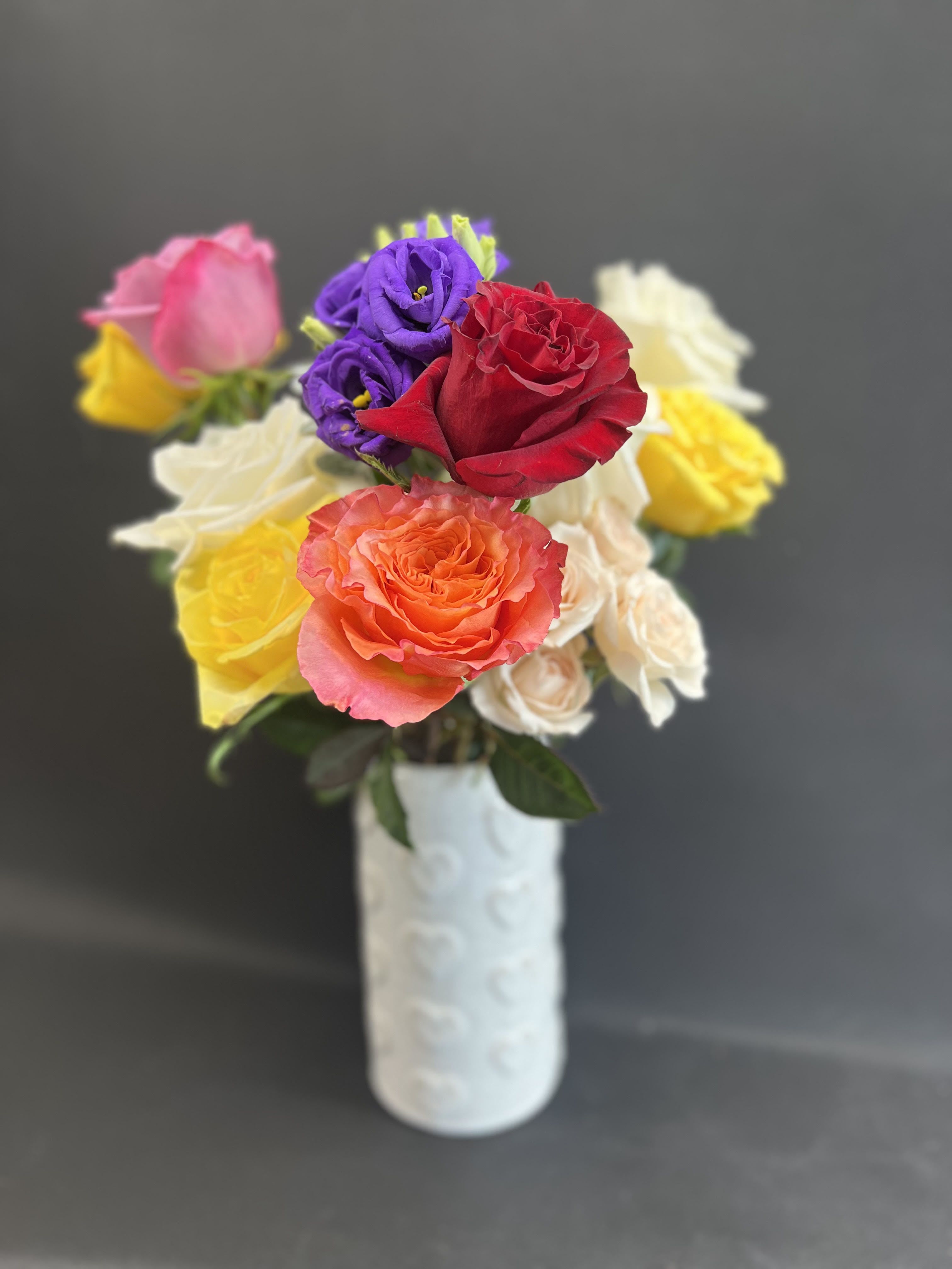 Bouquet of multicolored roses in a white vase
