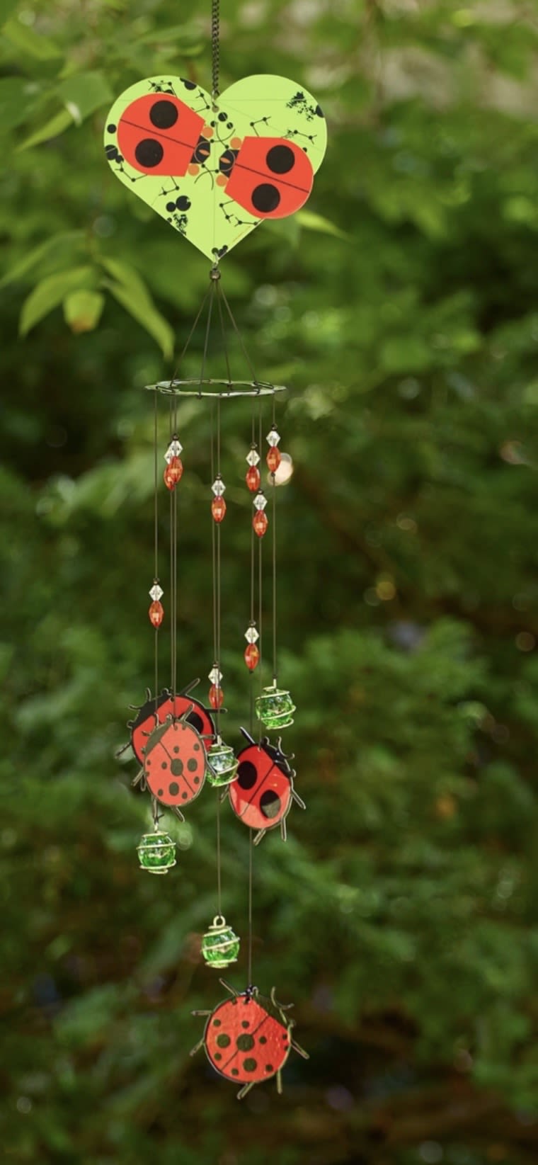 Ladybug Windchime  - Inspired by Charley Harper’s ladybugs, this spiral windchime mobile is a charming and classic add to any outdoor space. With simple geometric shapes, bold color, and a dash of wit, Harper distilled the essence of each creature he painted to its most important details in his unique minimal realist style.  ??????? ???????: • Ladybug image printed on front and back of steel plate • 4 ladybug chimes, marble, and crystal bead accents • Crafted from steel, acrylic beads, and glass • Includes swivel S hook for smooth spinning • Weather-resistant for year-round use • Ideal for patios, porches, and gardens Length: 30.25" Width: 3.5" Outdoor Decor | Weatherproof Yard Art | Whimsical Gifts | Garden Ornaments | Gifts for Gardeners | Seasonal Décor | Nature-Inspired Art