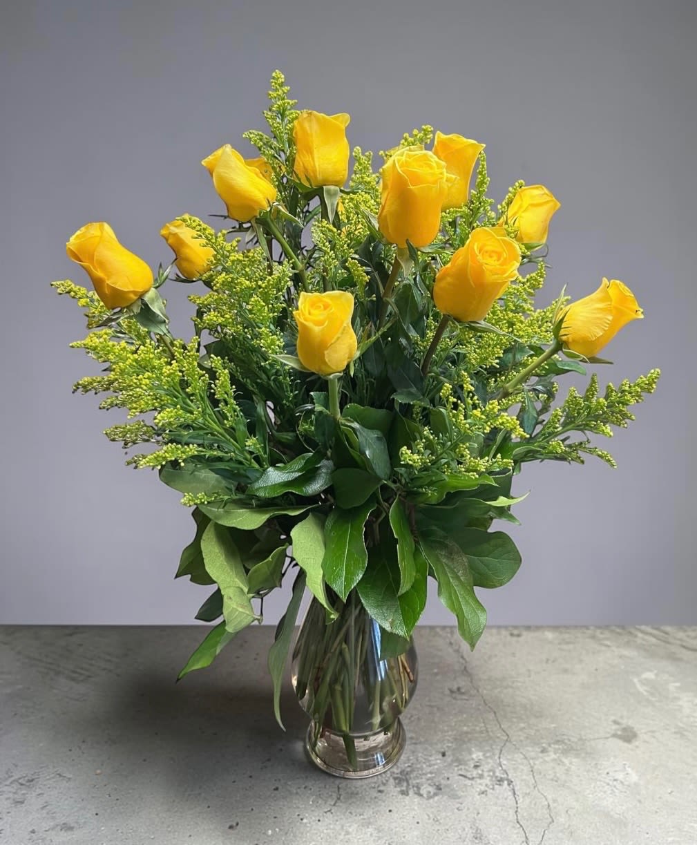 Dozen Yellow Roses - Brighten their day with a timeless bouquet of fresh yellow roses, beautifully arranged with lush greenery in a clear glass vase.
