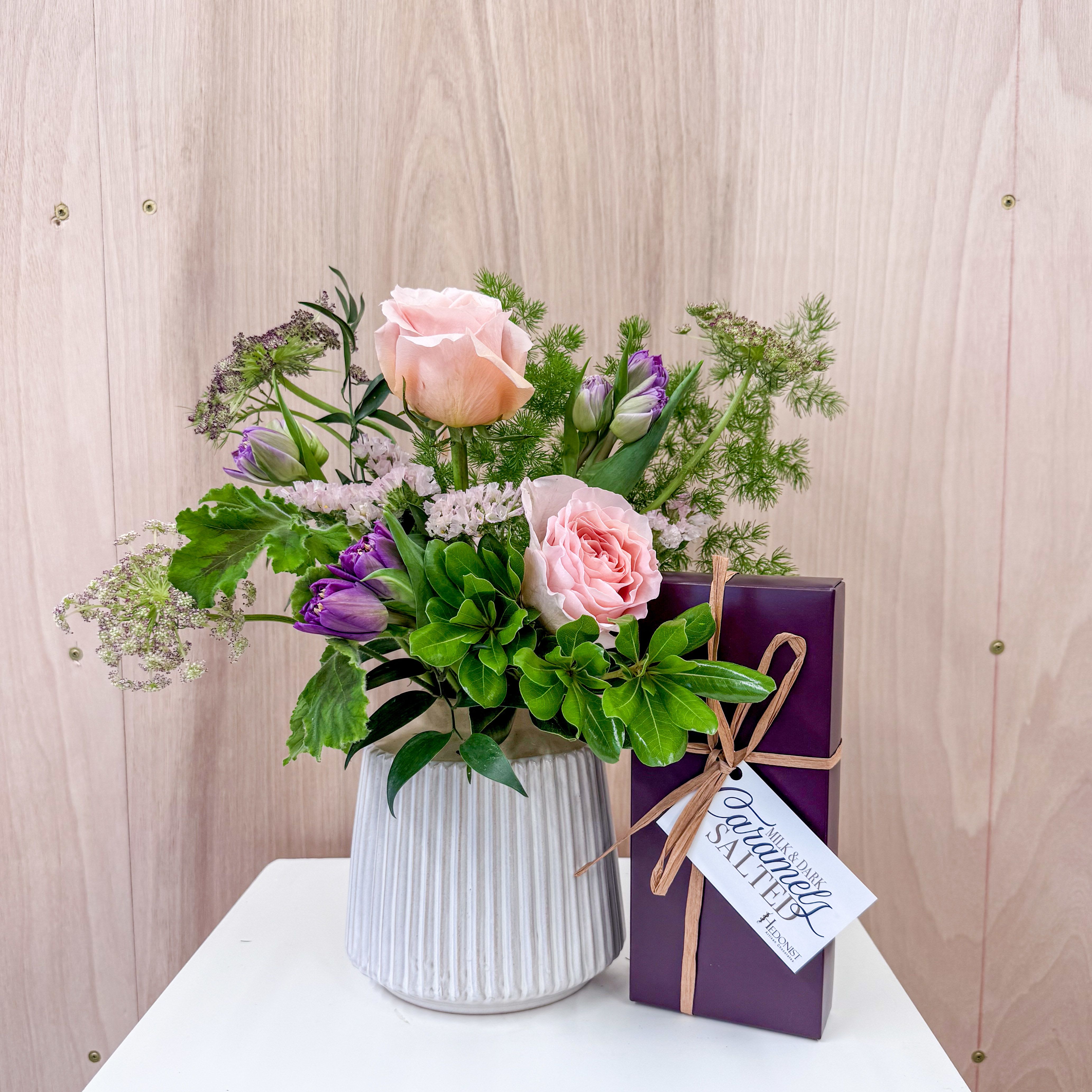 Sweet Surprise - One of our handcrafted ceramic vases with a beautiful spring arrangement paired with a box of Hedonist Salted Caramels. Upgrade to deluxe for additional premium blooms.