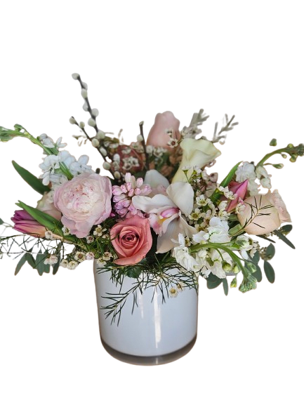 Blushing Rose Meadow - A soft and romantic arrangement featuring blush roses, delicate hyacinth, Cymbidium orchids, stock, tulips, peonies, wax flower and pussy willow branches; airy seasonal blooms, and fresh greenery gathered in a modern white vase. Designed with graceful texture and gentle pastel tones, Blushing Rose Garden brings timeless elegance and sweet charm to birthdays, celebrations, or simply brightening someone’s day.