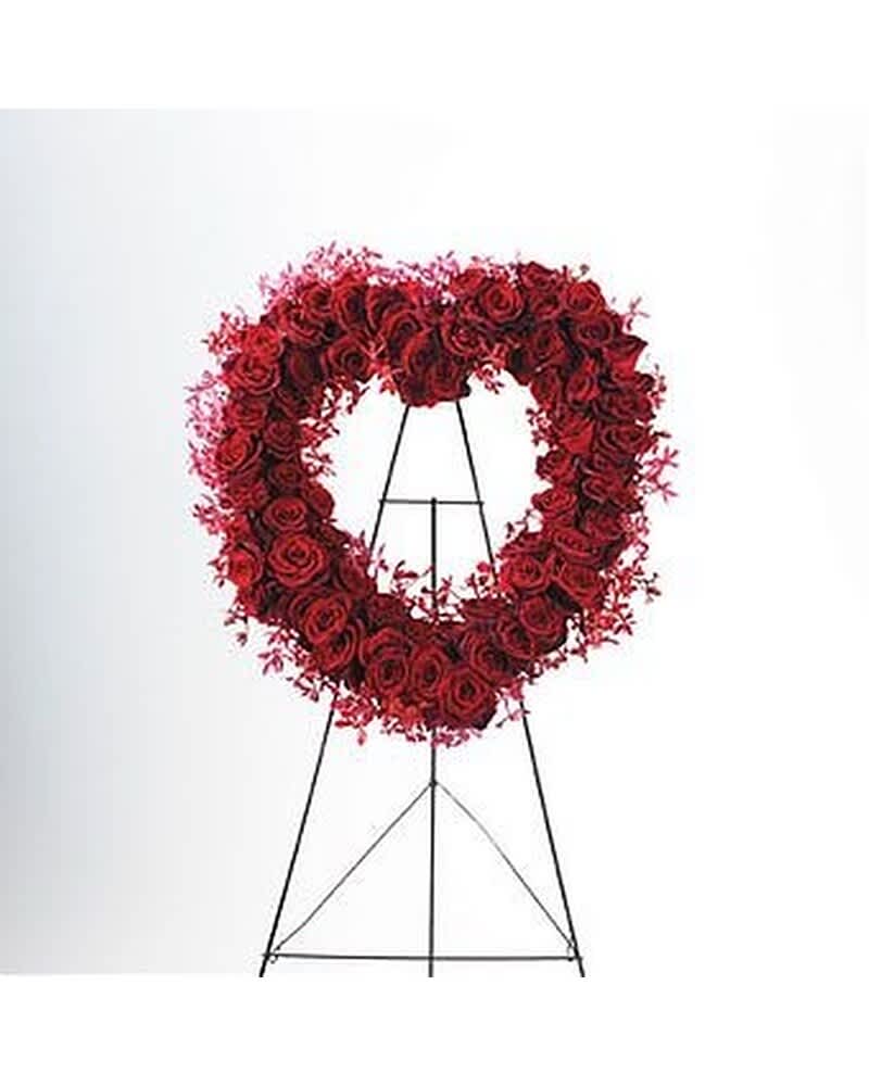 Heart-shaped wreath of red roses on a tall black metal easel