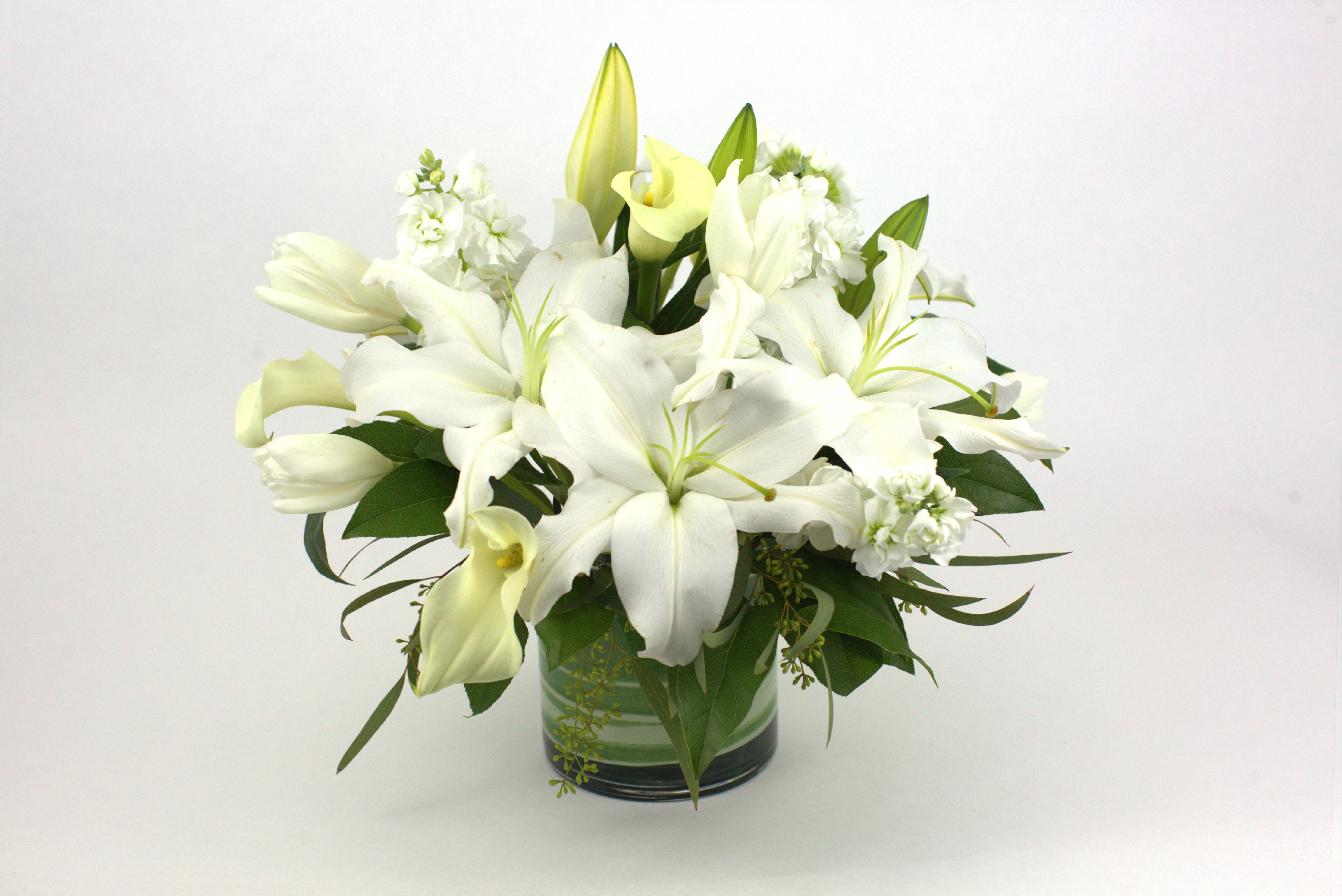 White lilies and calla lilies arranged in a glass vase